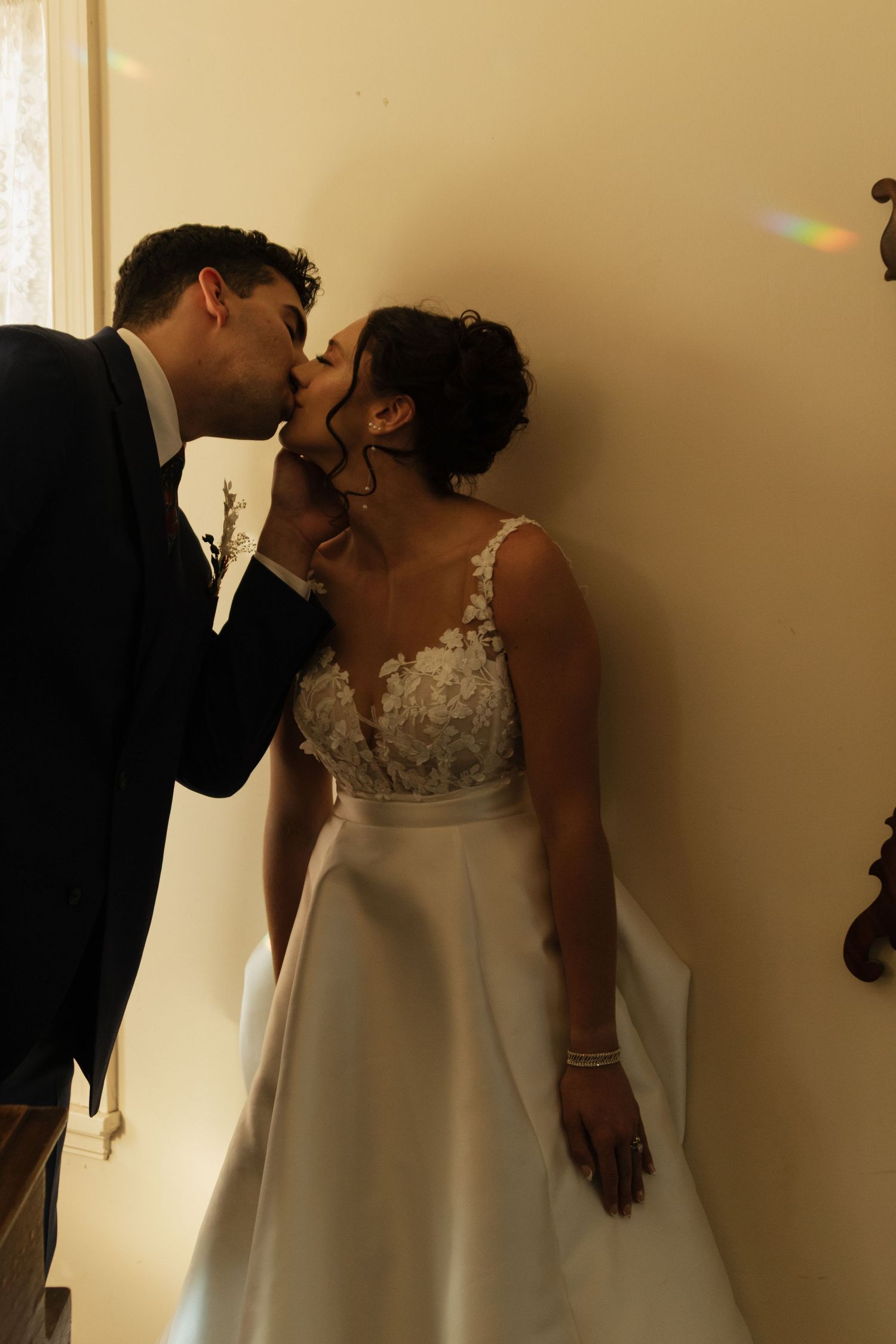 Intimate wedding moment captured in dramatic shadow and warm lighting.