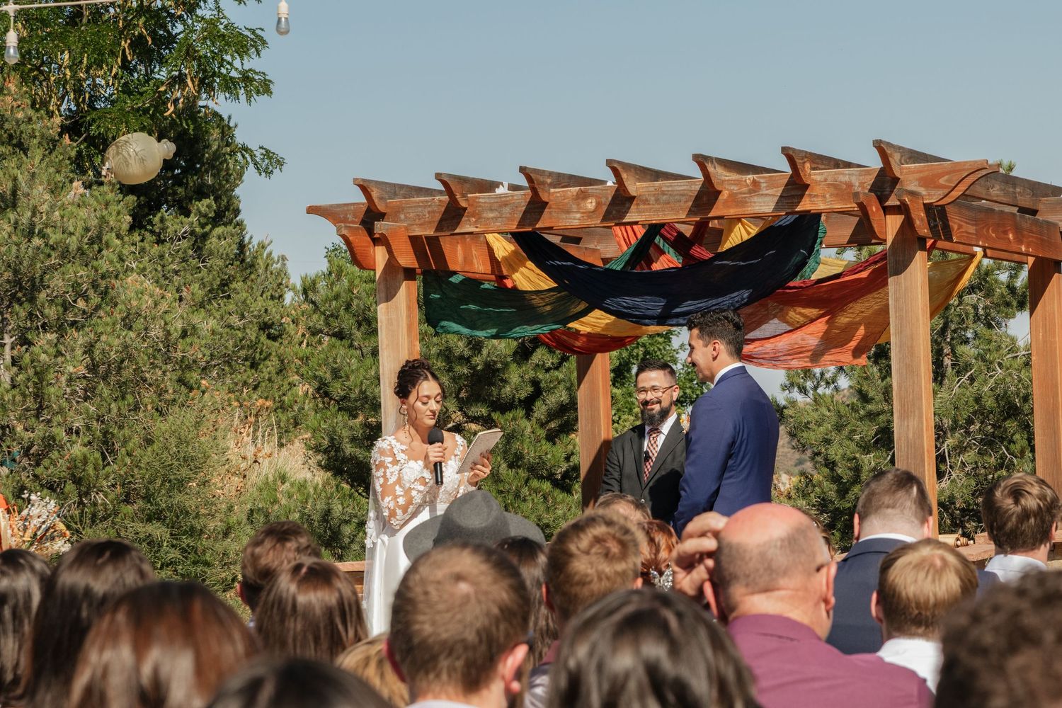 Wooden pergola ceremony setup against a mountain backdrop with blue sky.