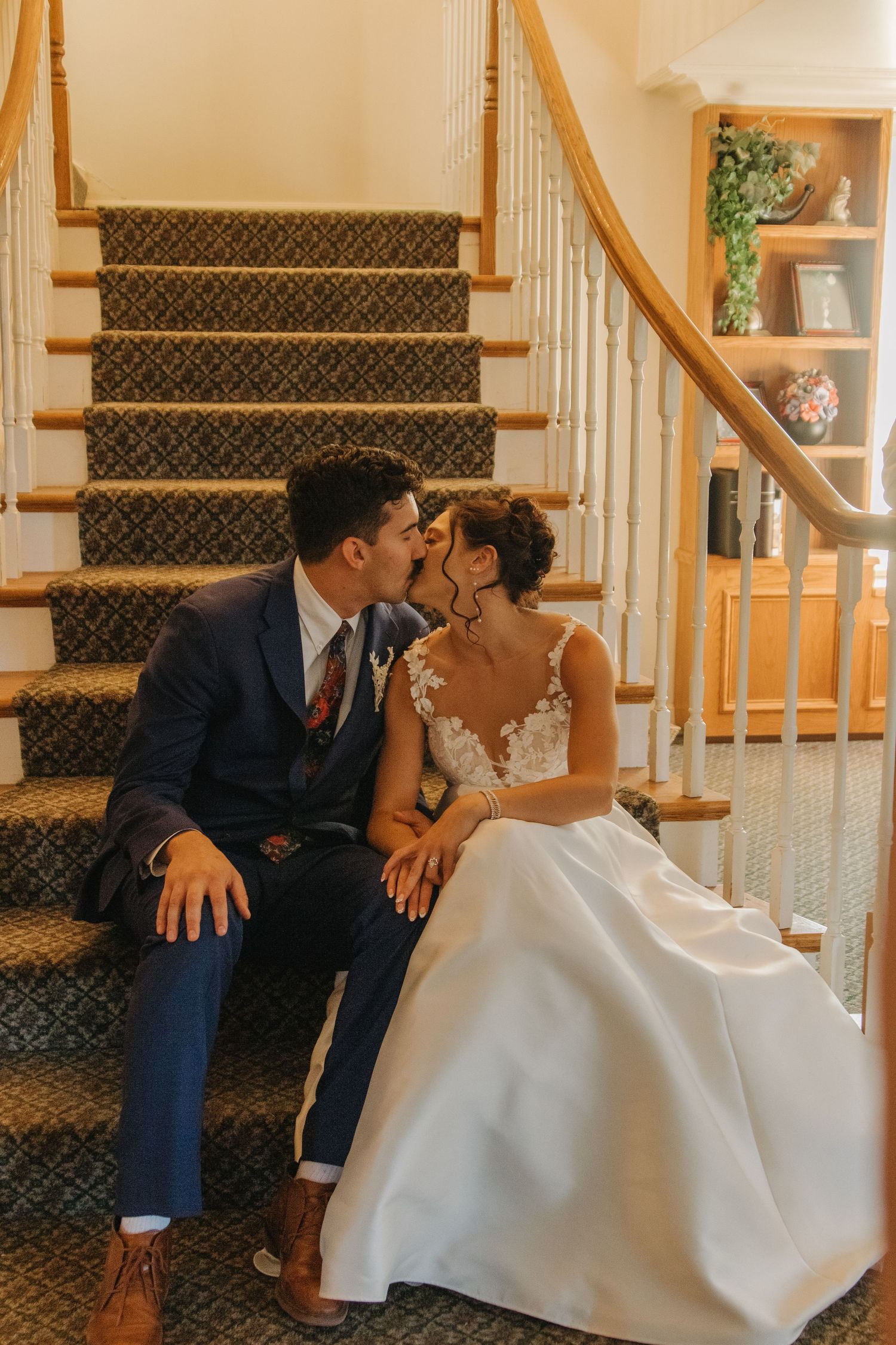 Wedding couple posing on elegant carpeted stairs with wooden railings.