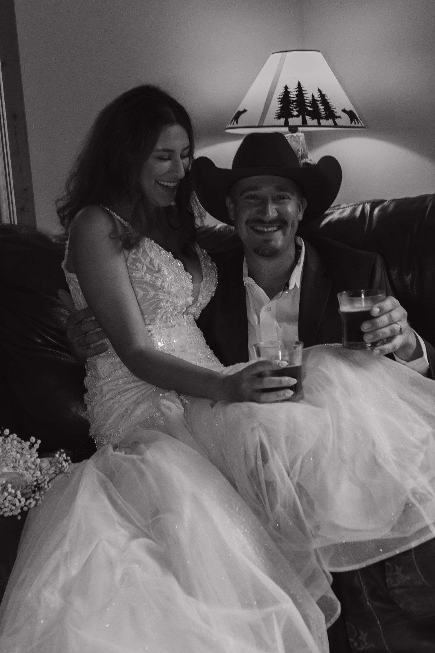 Newlyweds share drinks and laughter while relaxing indoors after their wedding ceremony.