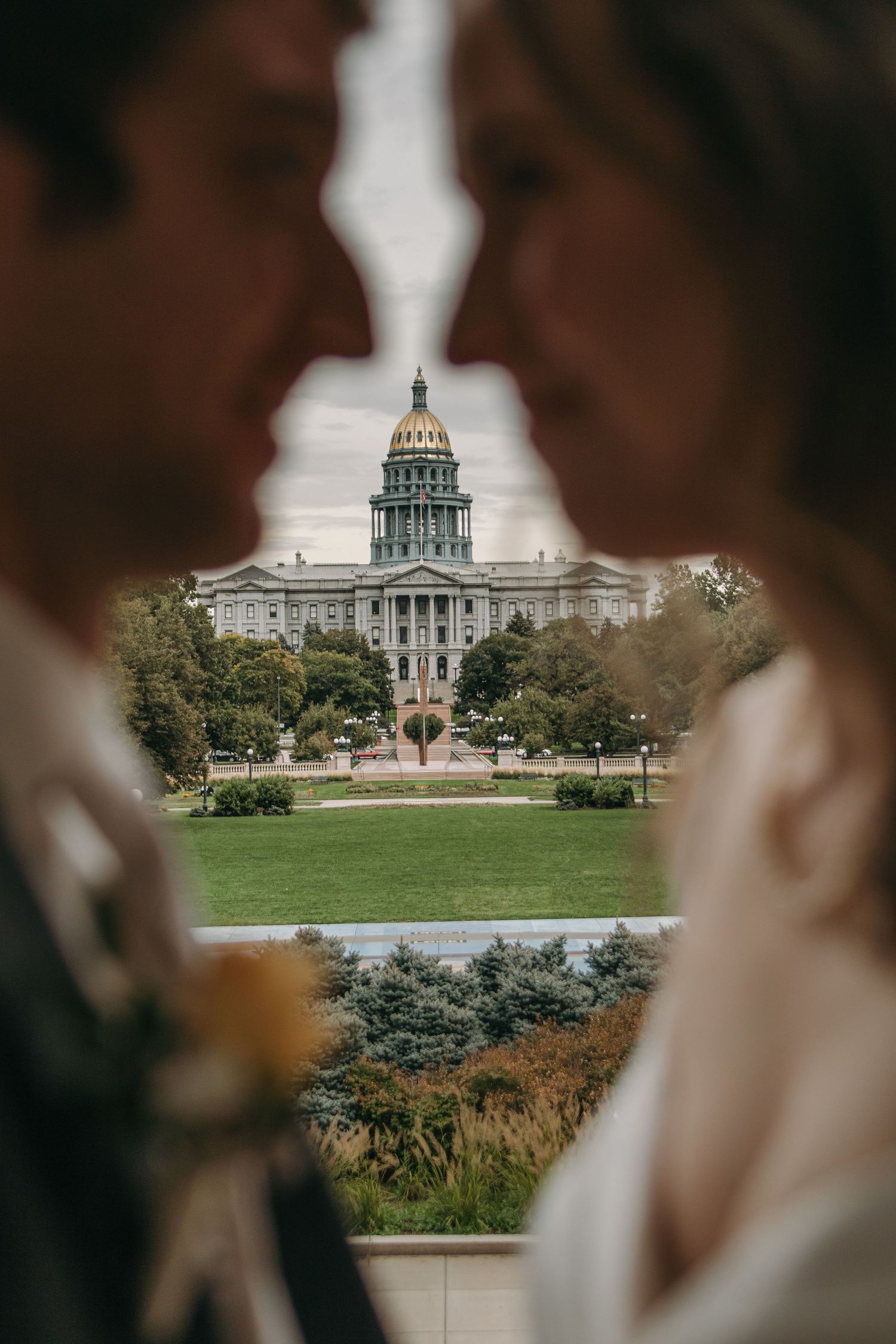 The Colorado State Capitol building viewed through blurred silhouettes in the foreground.