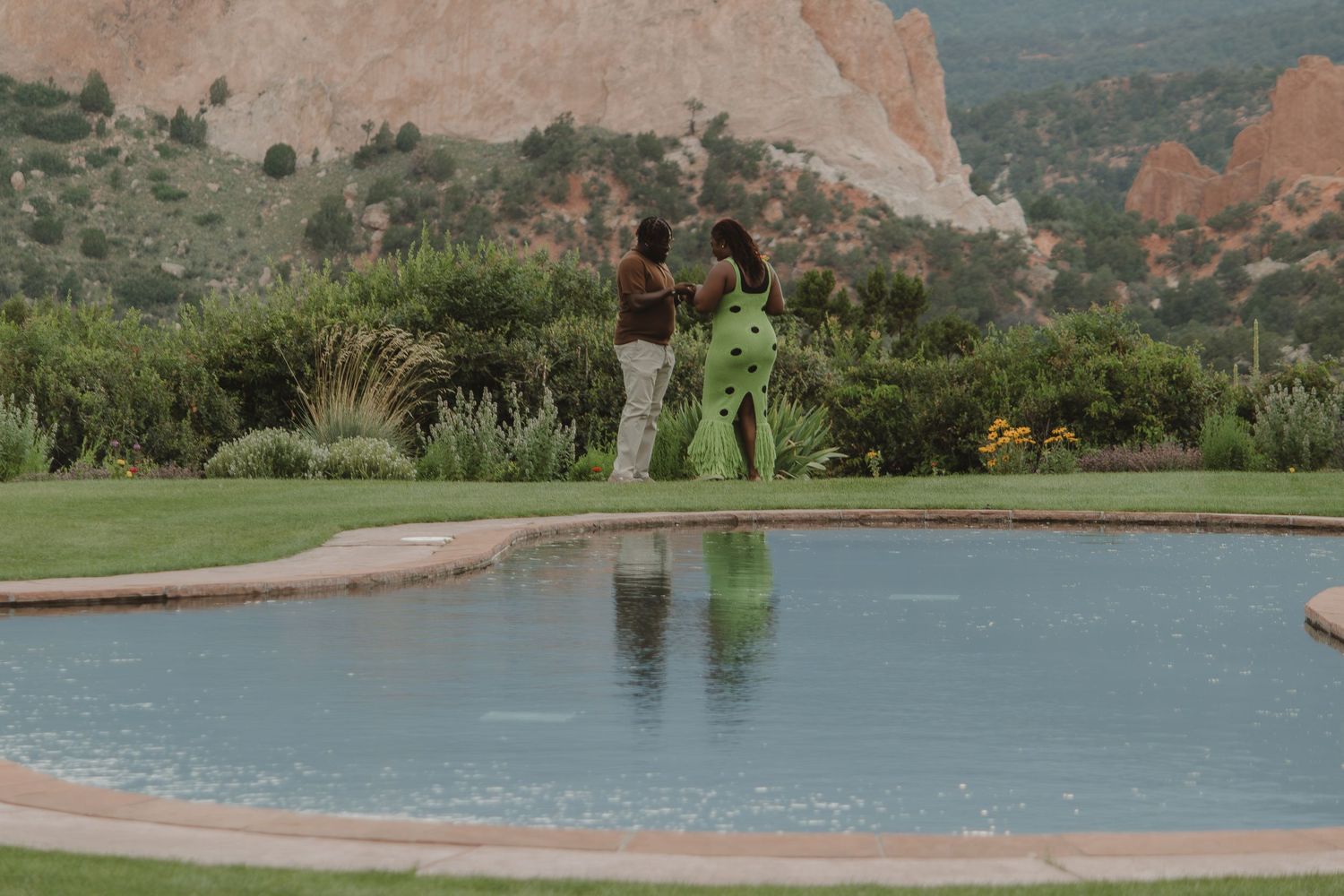 A scenic view of Garden of the Gods with a curved pool and red rock formations in the background.