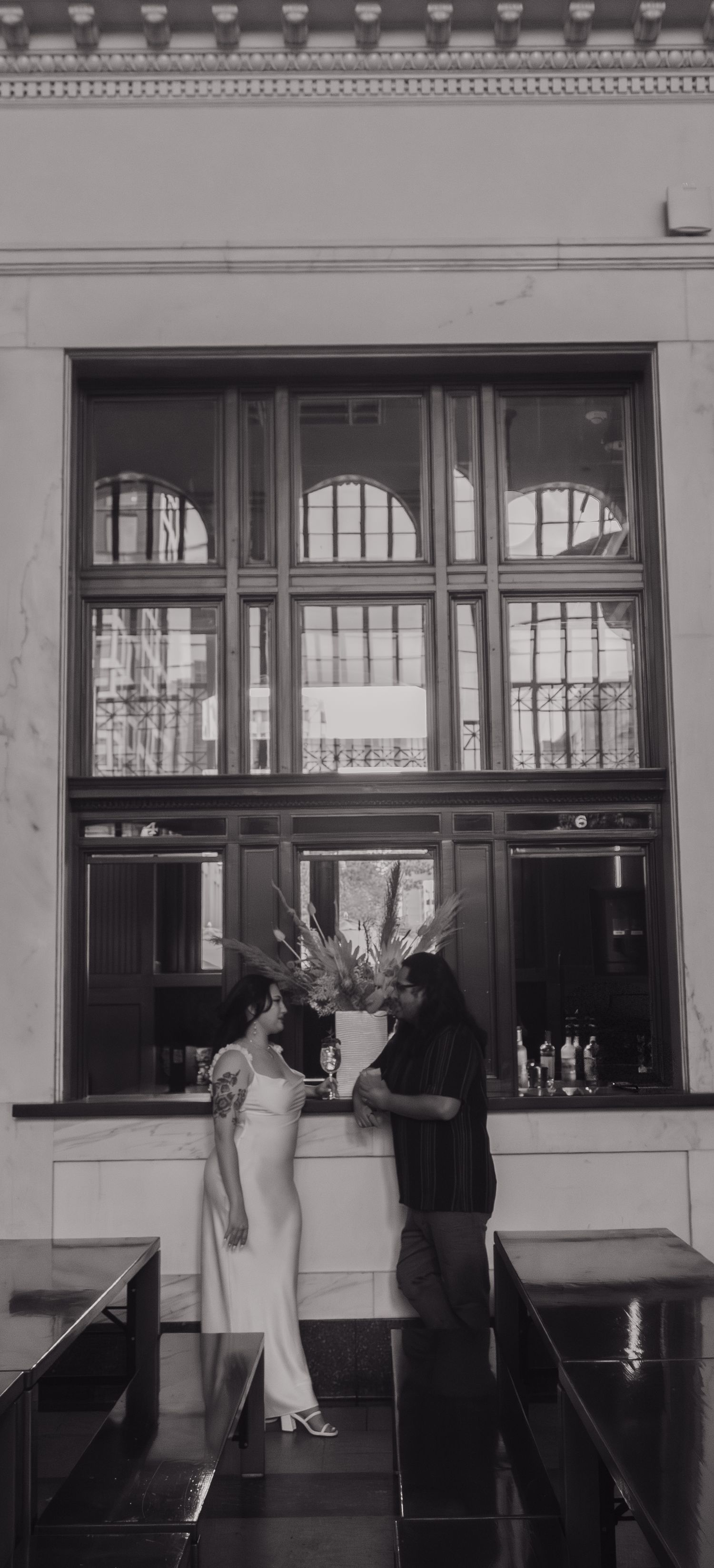 Black and white photo series showing a couple in formal wear posing by windows in an art deco building.