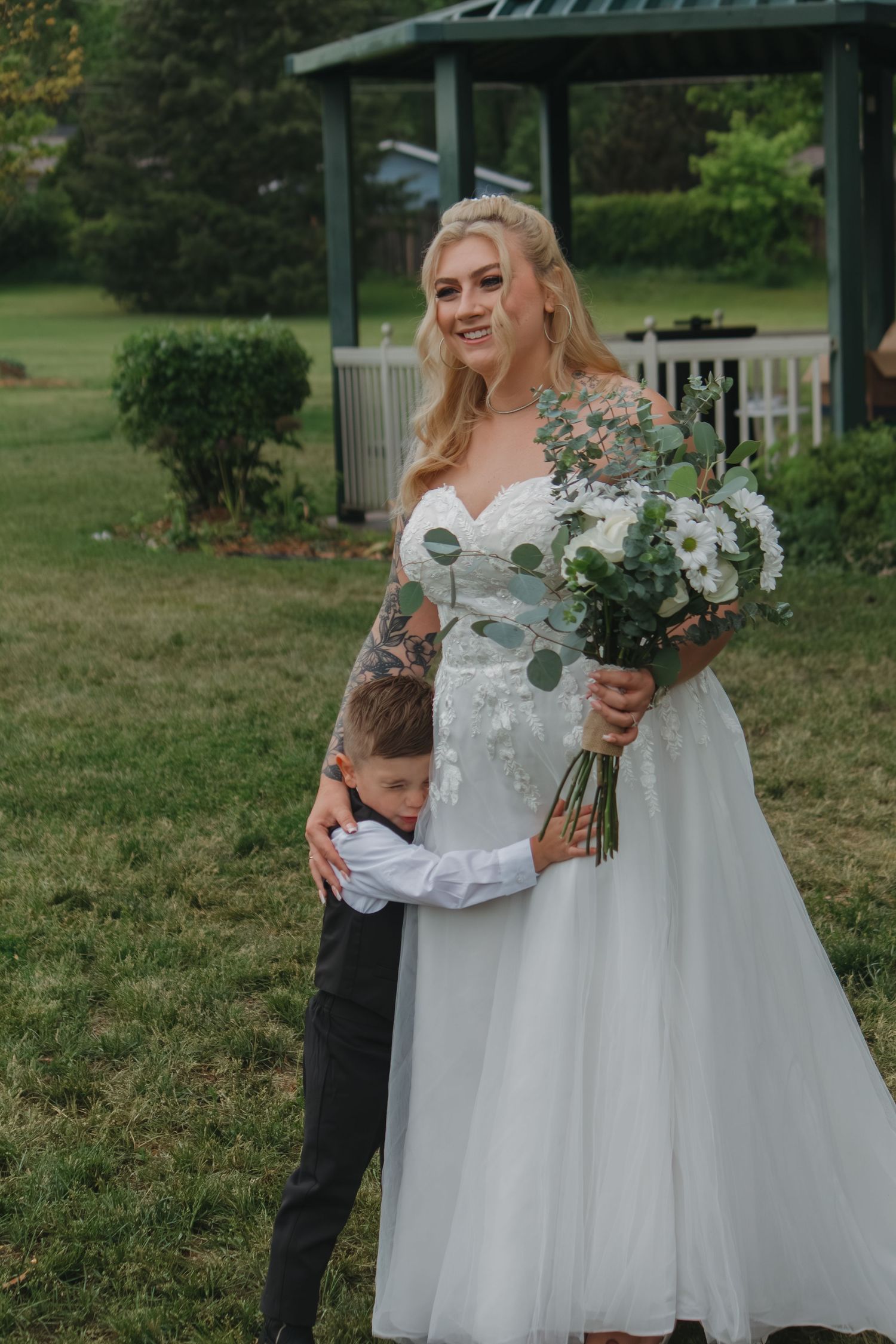 White wedding dress and formal wear shown against green outdoor garden backdrop.