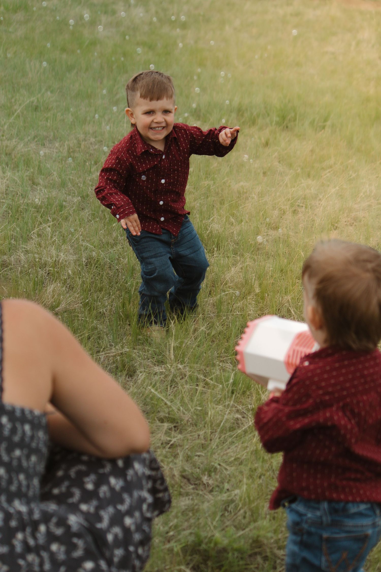 Playful outdoor scene with children in matching red shirts playing in tall grass.