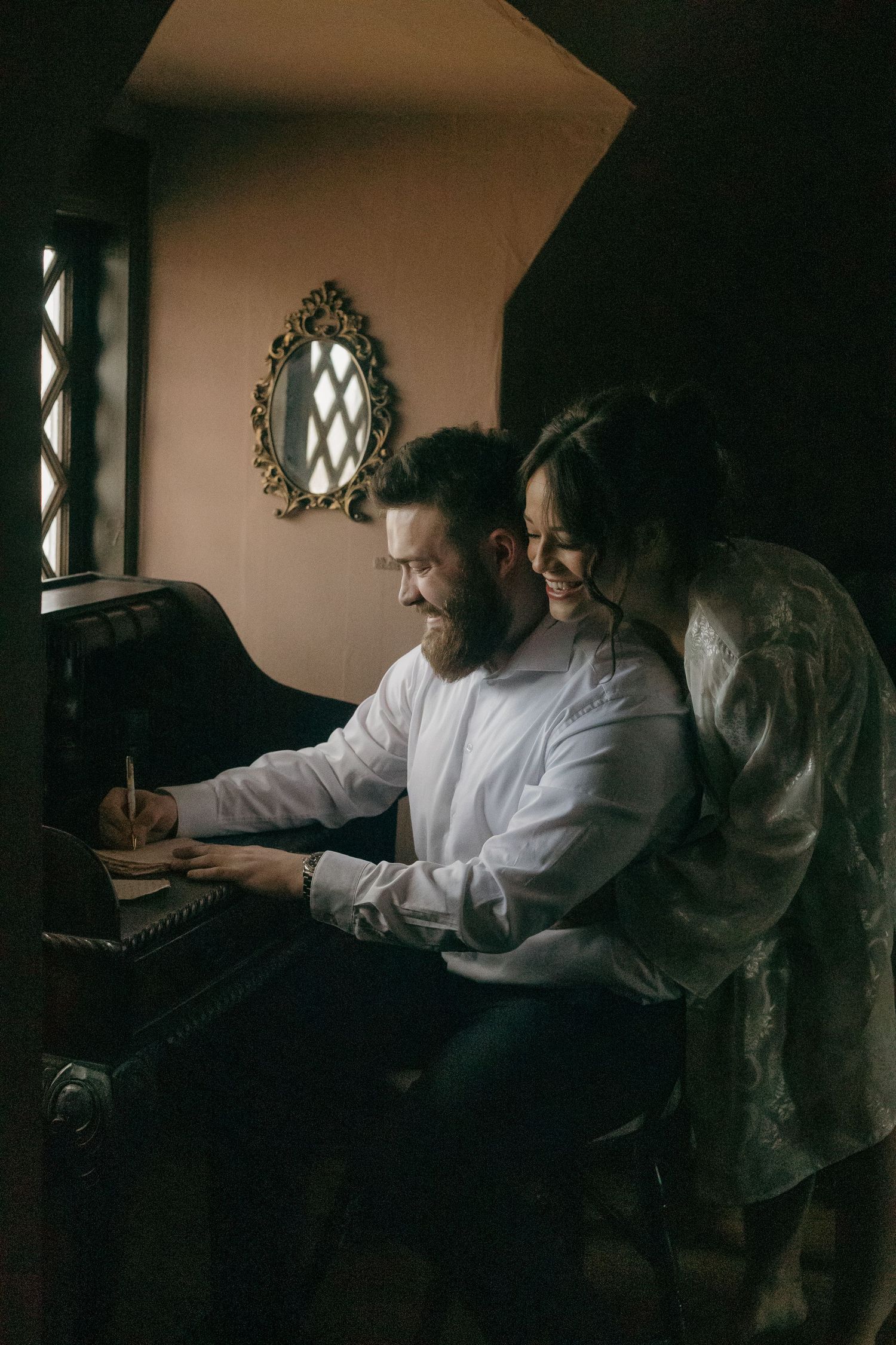 People seated by a window in a dimly lit room working on documents.