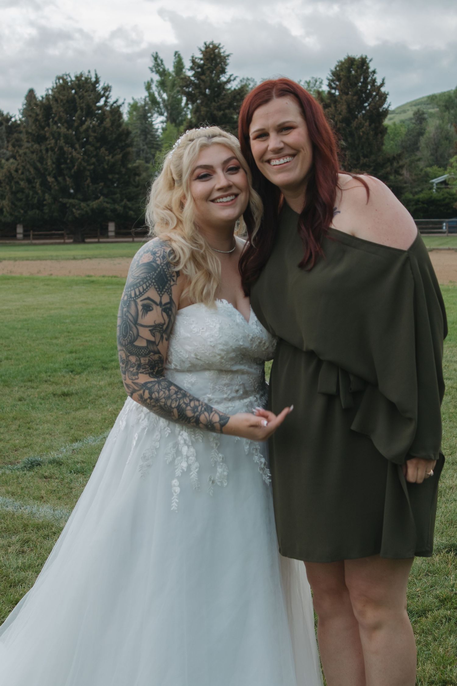 Two people in contrasting outfits embrace while standing in a grassy field.