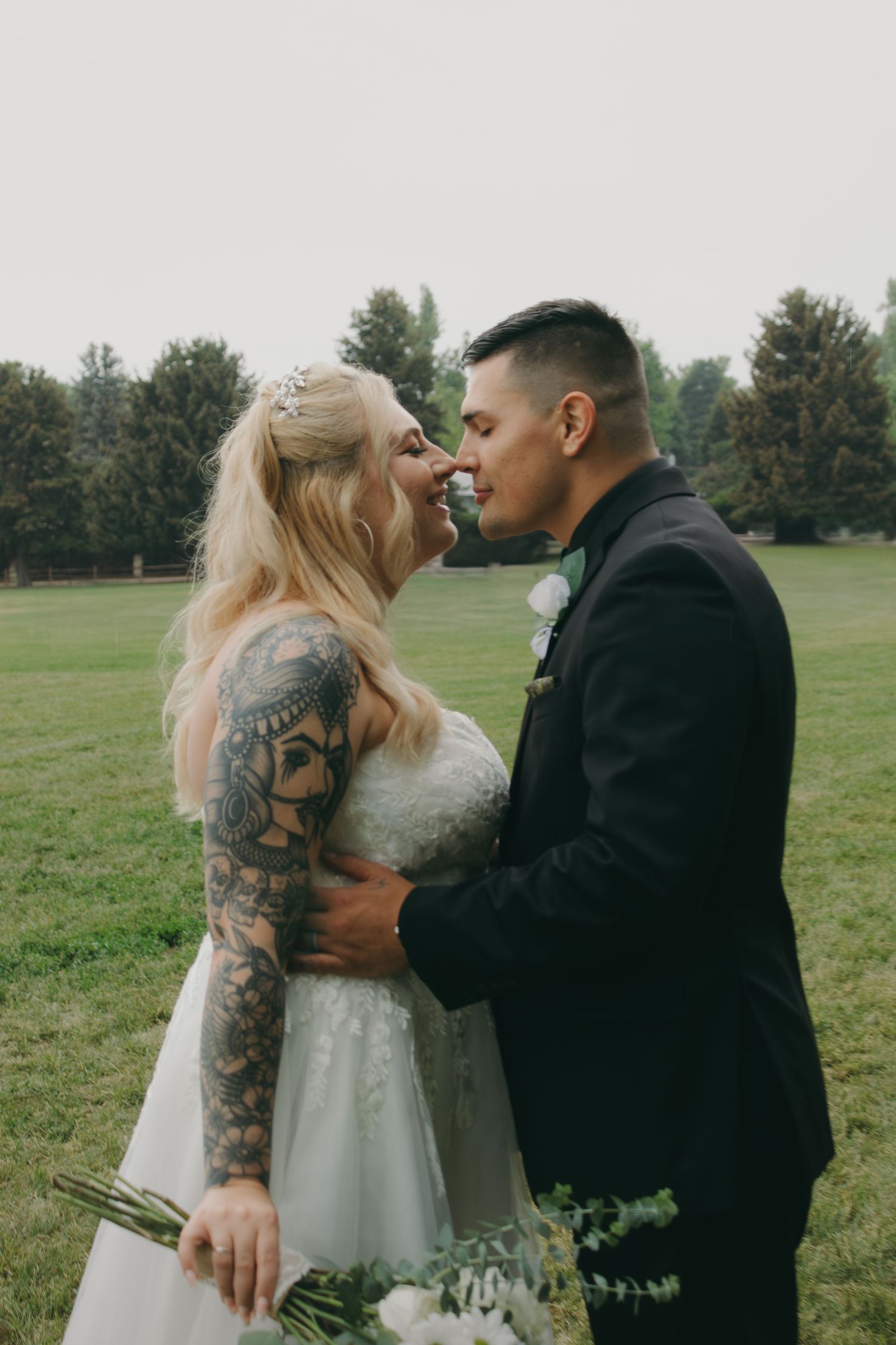 A candid wedding portrait showing an intimate moment between newlyweds in an outdoor setting.