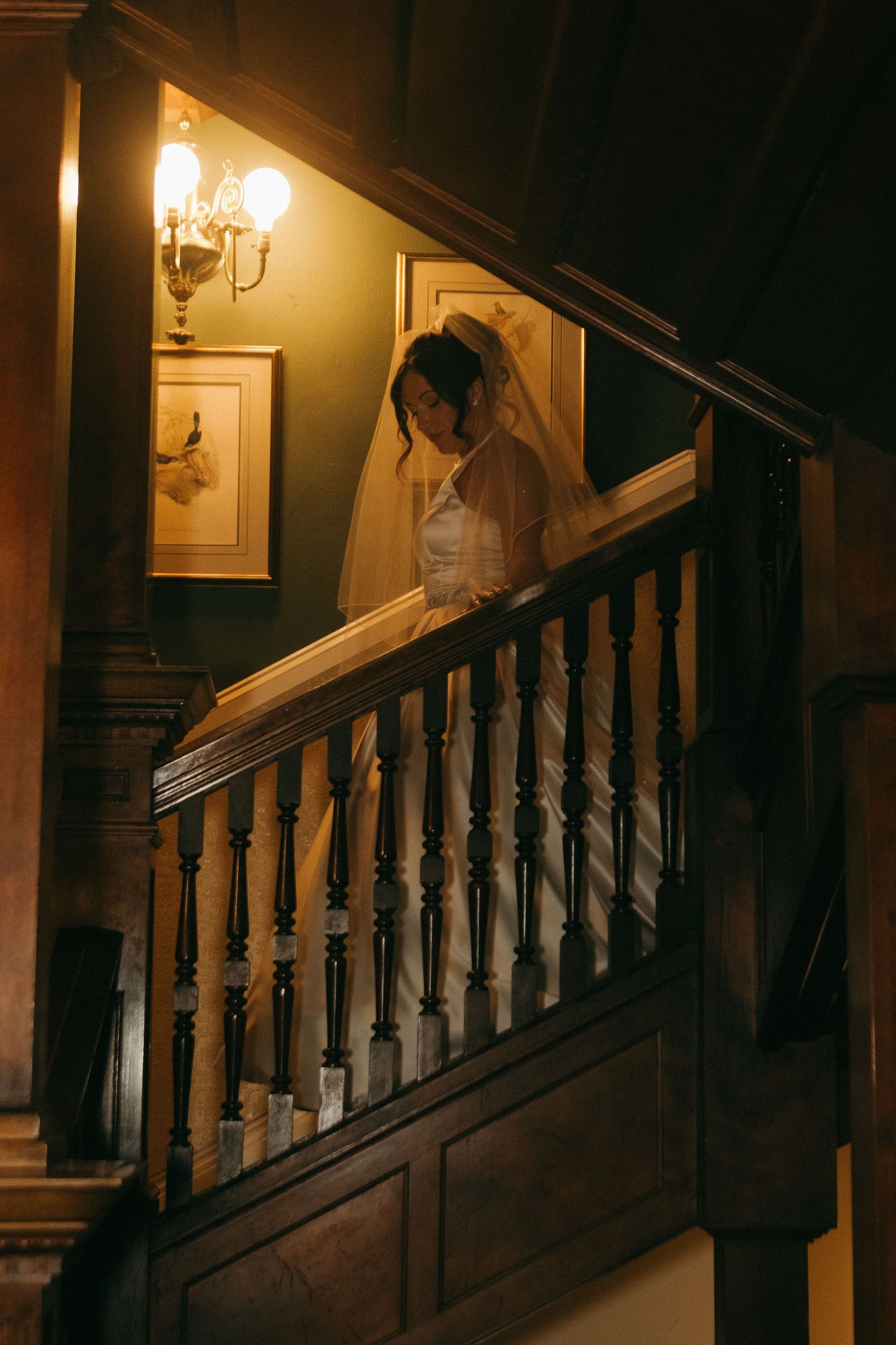 A warm, atmospheric scene on a wooden staircase with vintage wall sconces casting golden light in an old house.