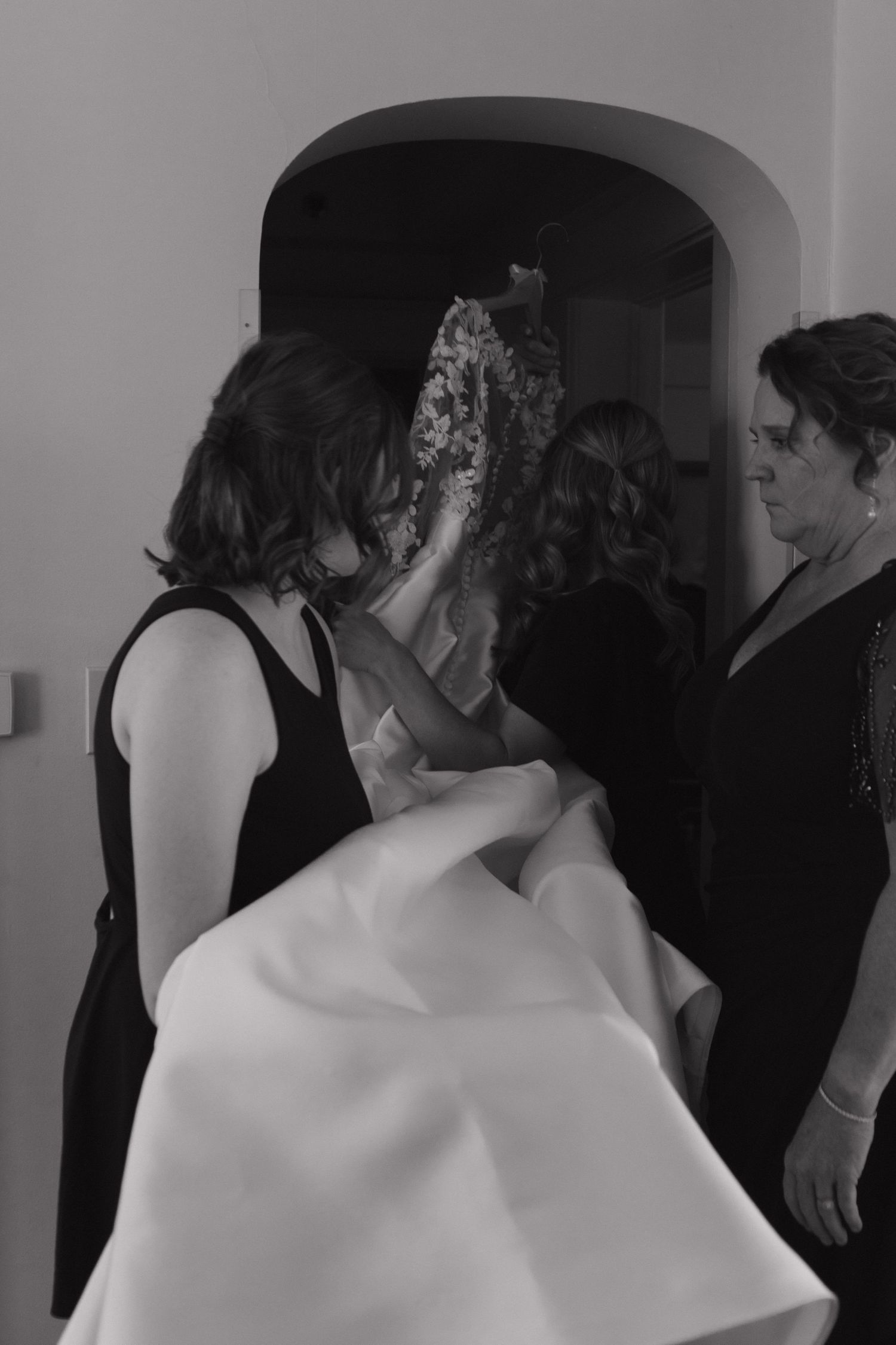 People gathered in formal black attire standing in an interior space.
