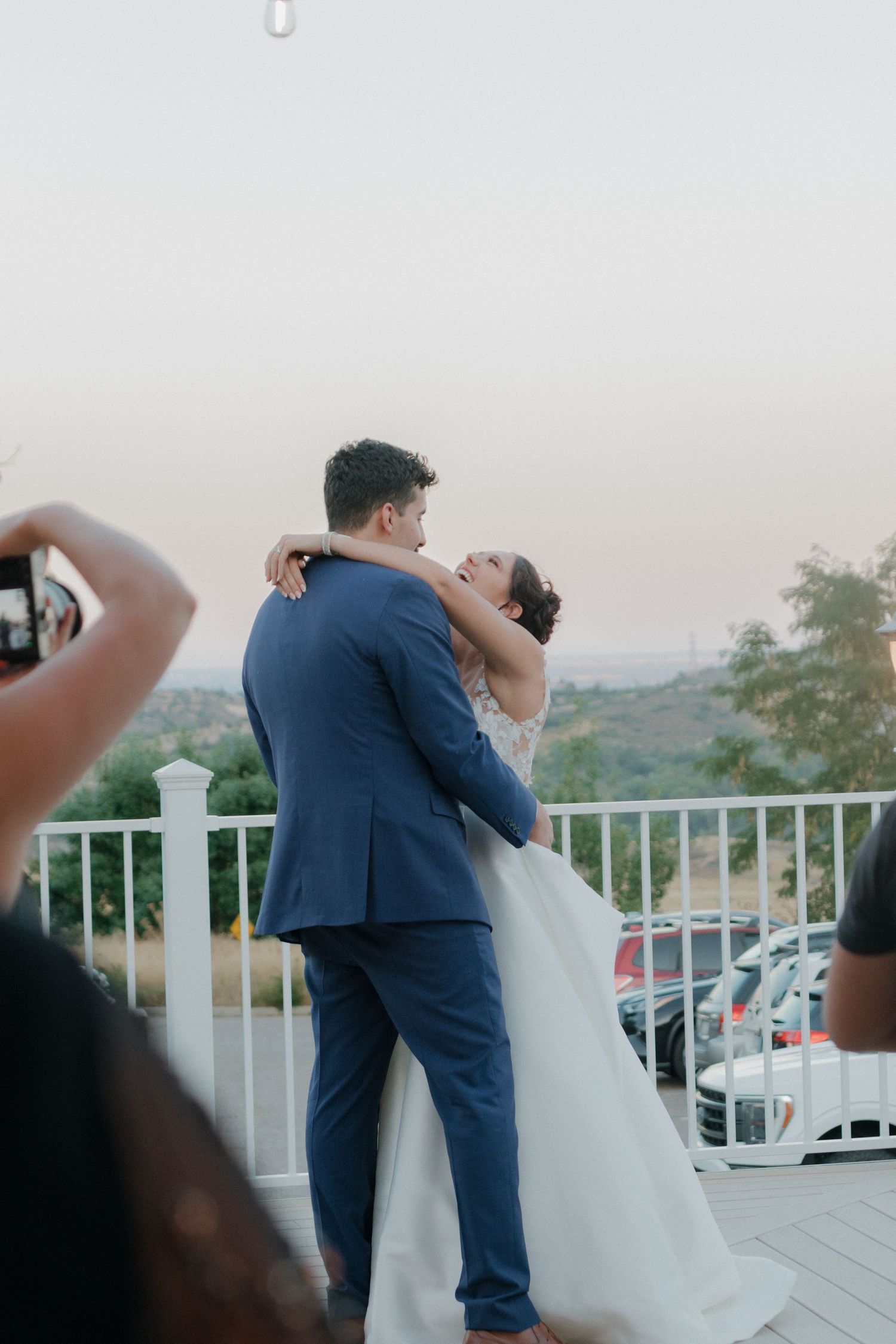 A tender dipping pose against a white railing with scenic mountain views in the distance.