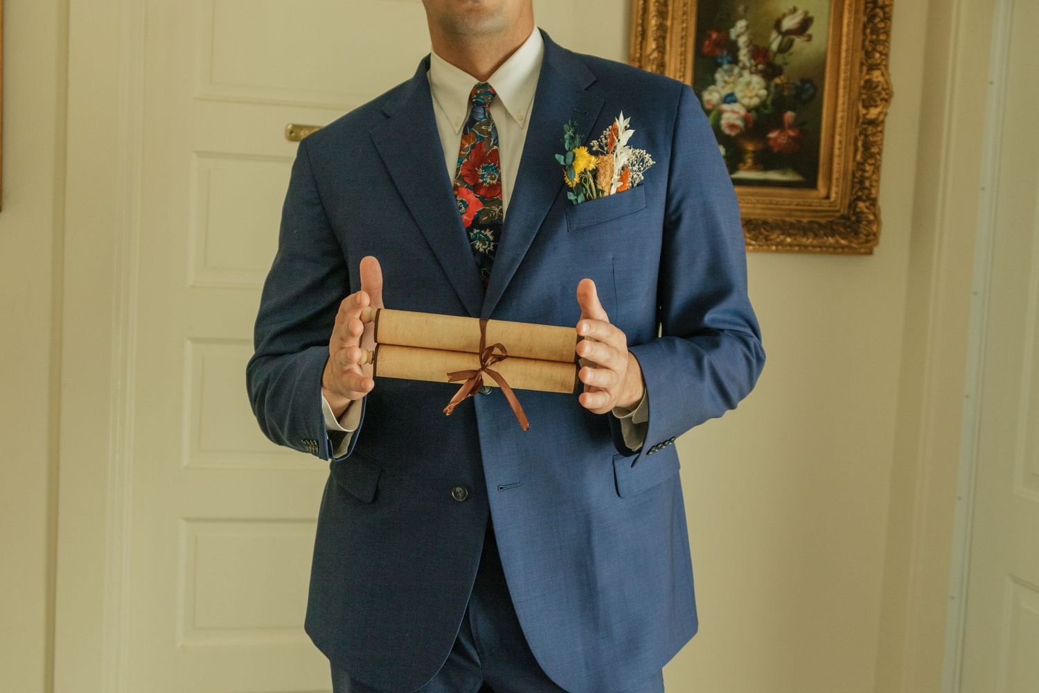 Person wearing navy blue suit with colorful tie and boutonniere in formal setting.