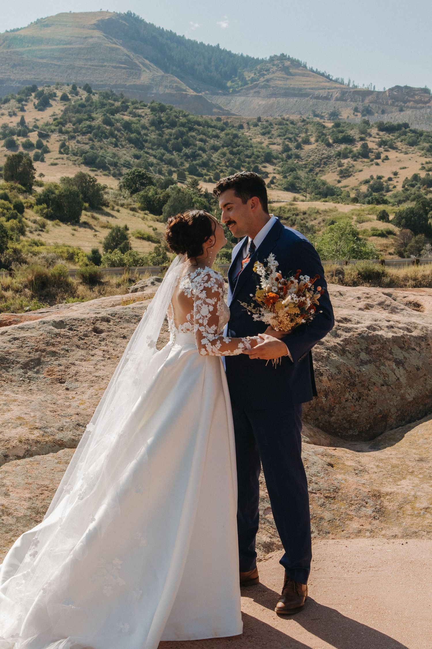 Newlyweds share a romantic moment on a mountain overlook with scenic views.