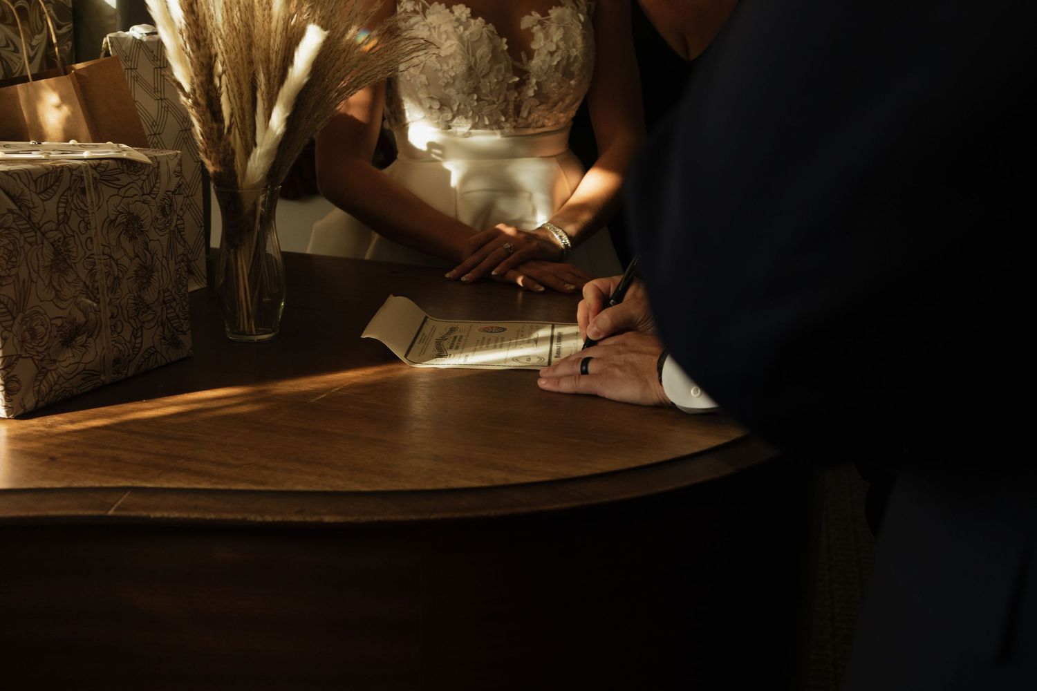 Close-up of hands gently touching in dim lighting during intimate wedding moment.