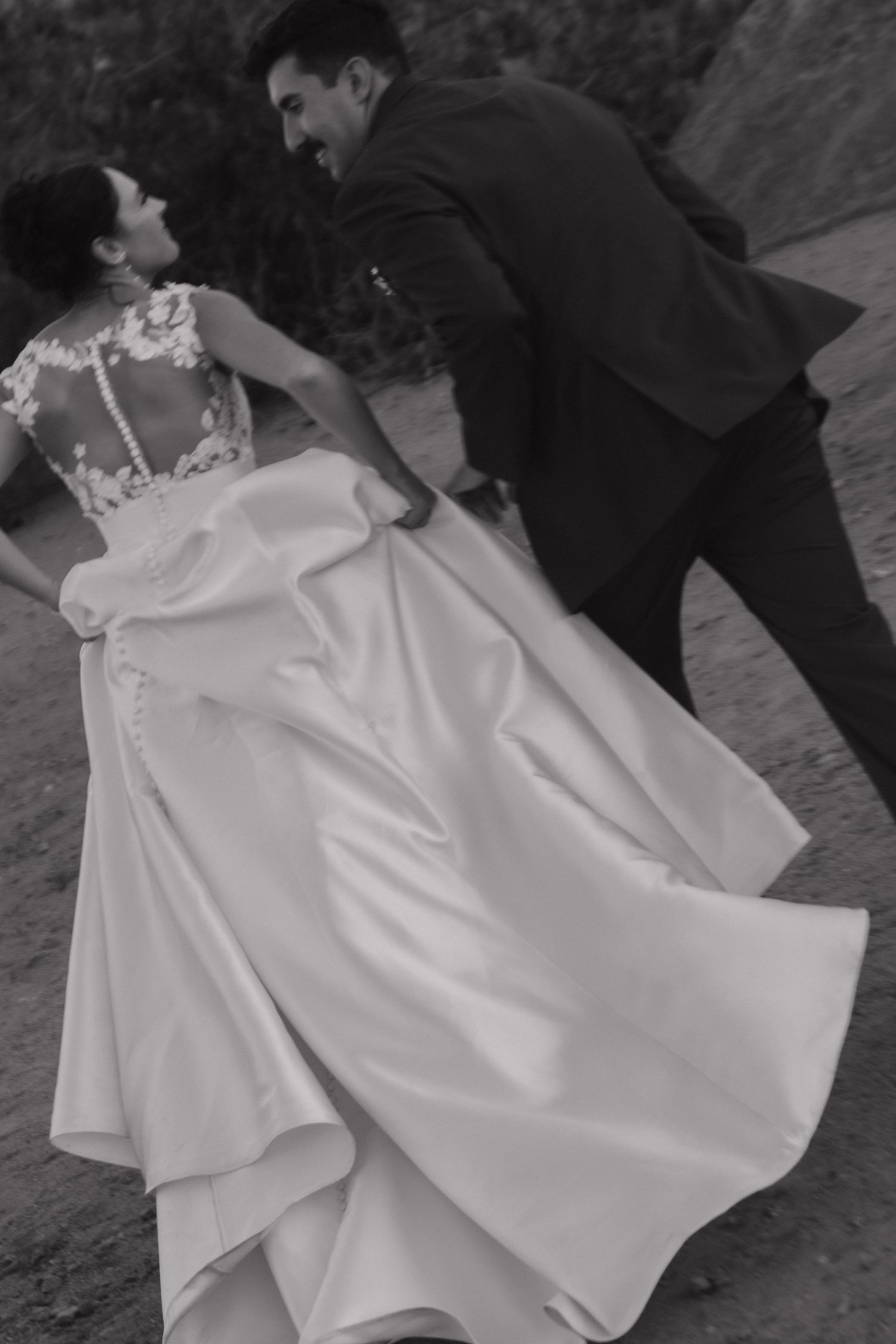 A flowing white wedding dress twirls gracefully in black and white photography.