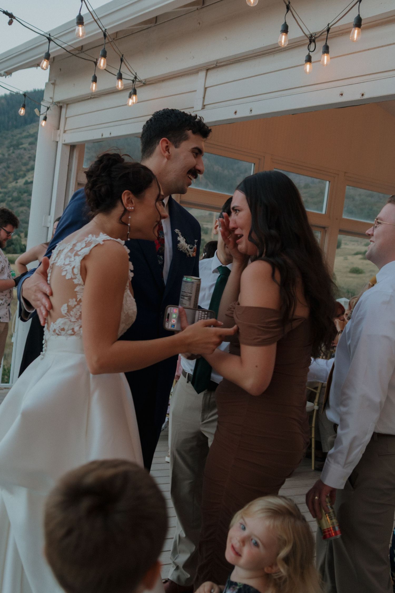 Wedding reception dance floor with string lights overhead as couples celebrate together.