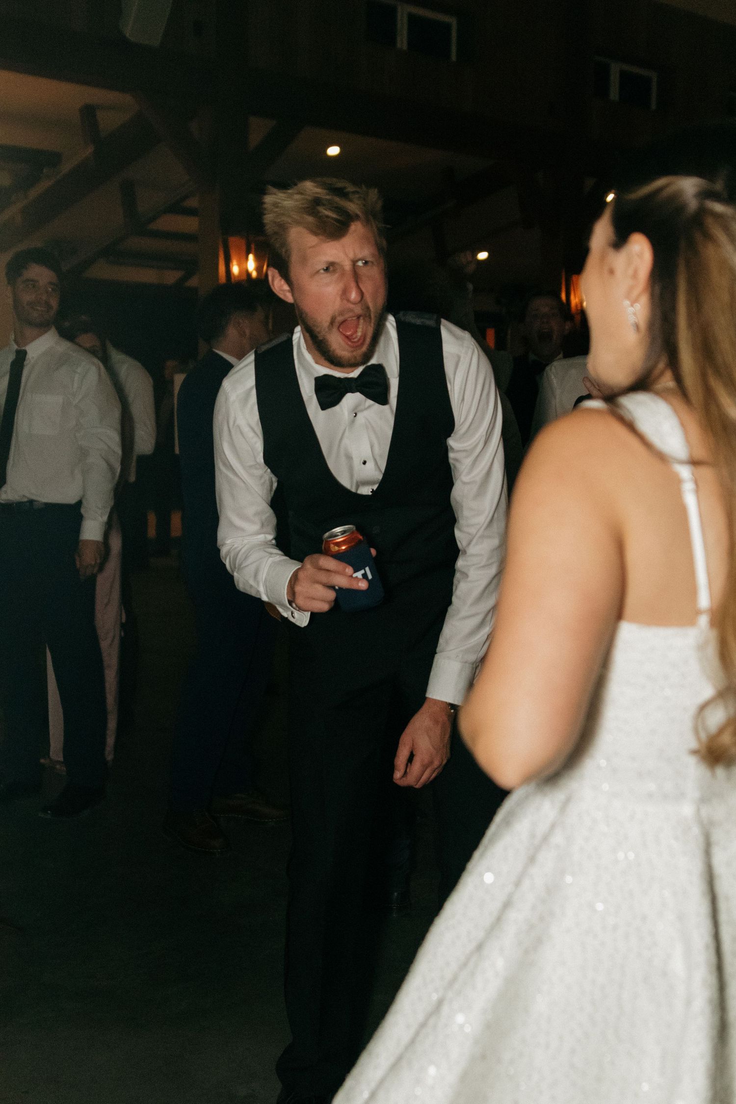 Wedding reception dance floor scene with guests in formal attire.