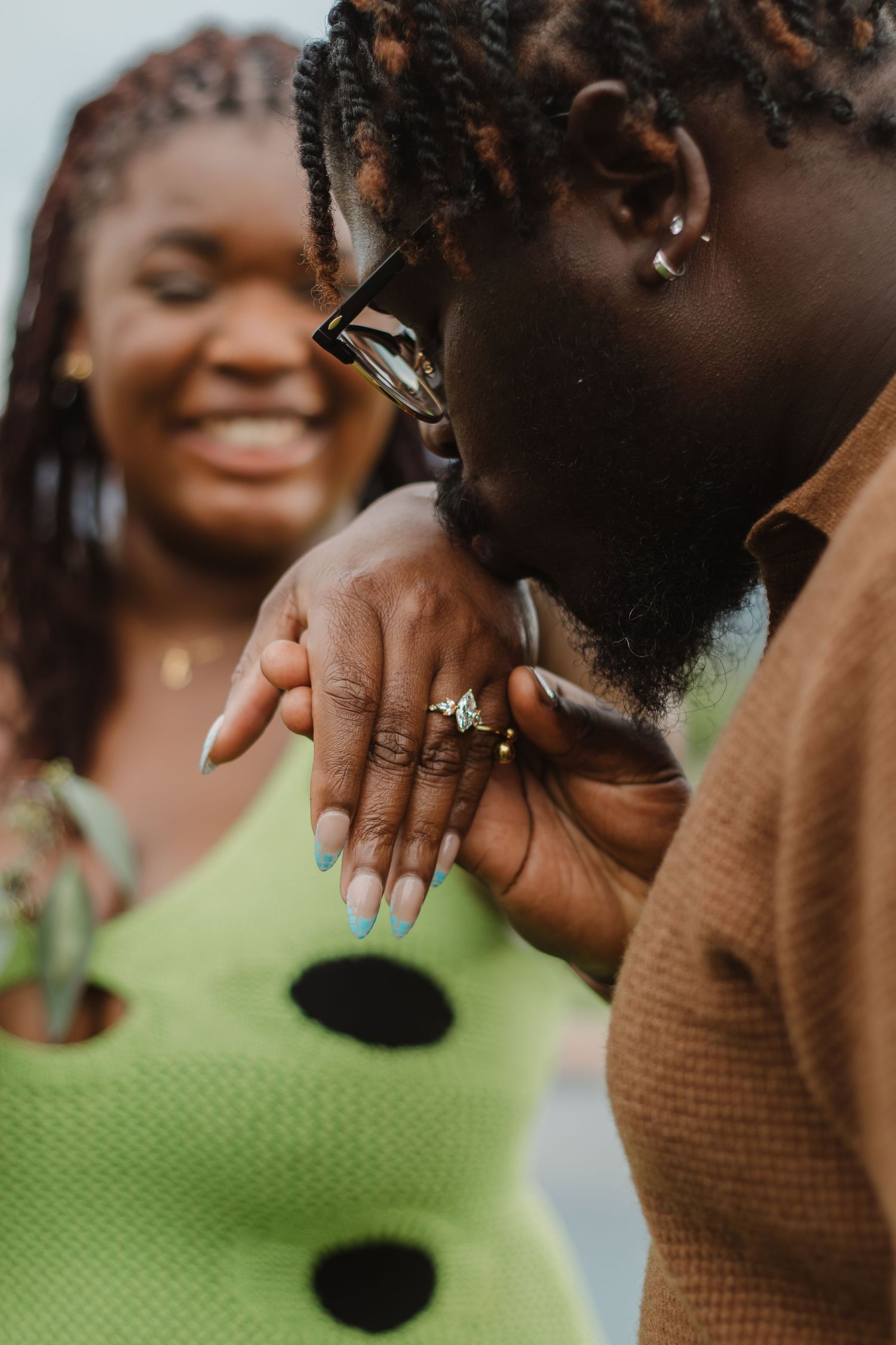 Close-up shot of an engagement ring being shown off against a lime green polka dot dress.