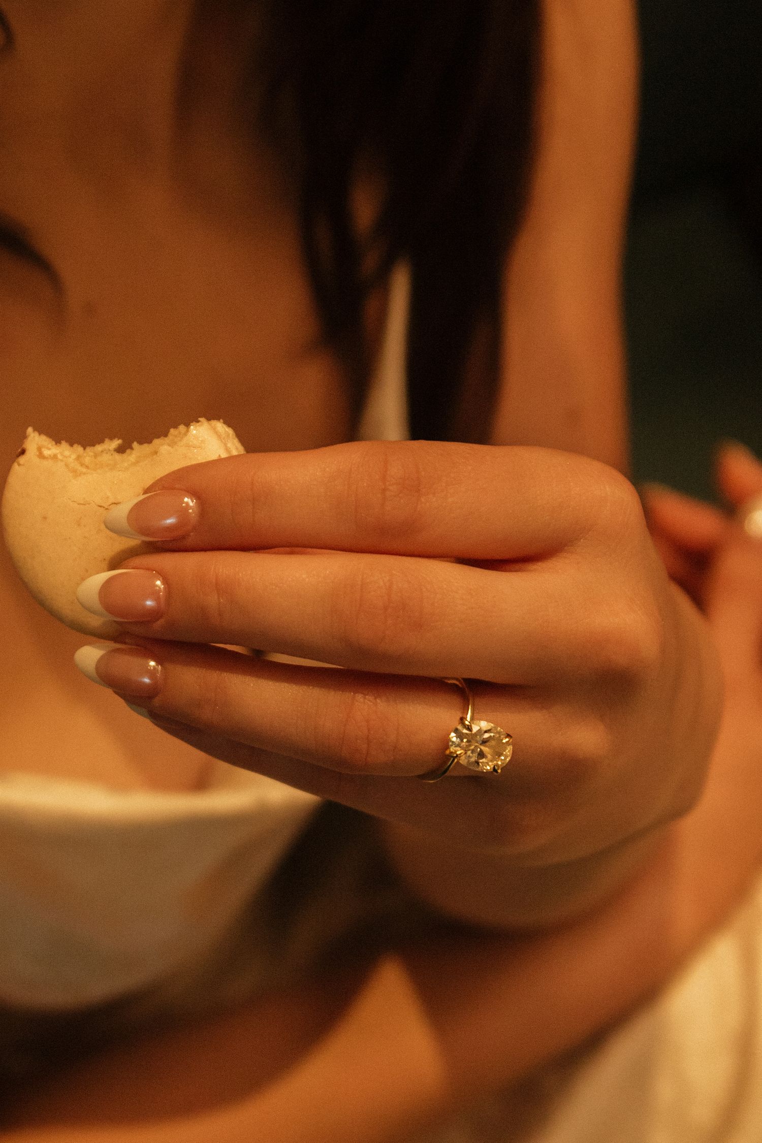 Hand with manicured nails wearing an elegant engagement ring.