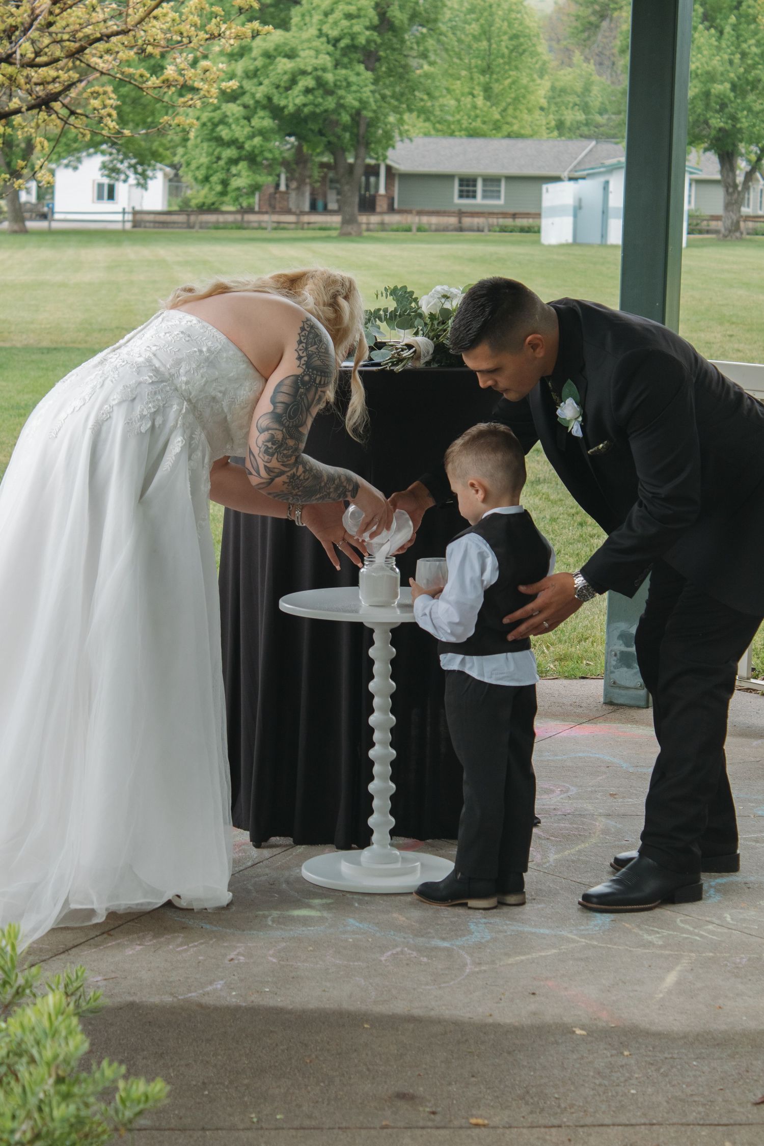 Wedding party members bending down to sign documents during an outdoor ceremony.