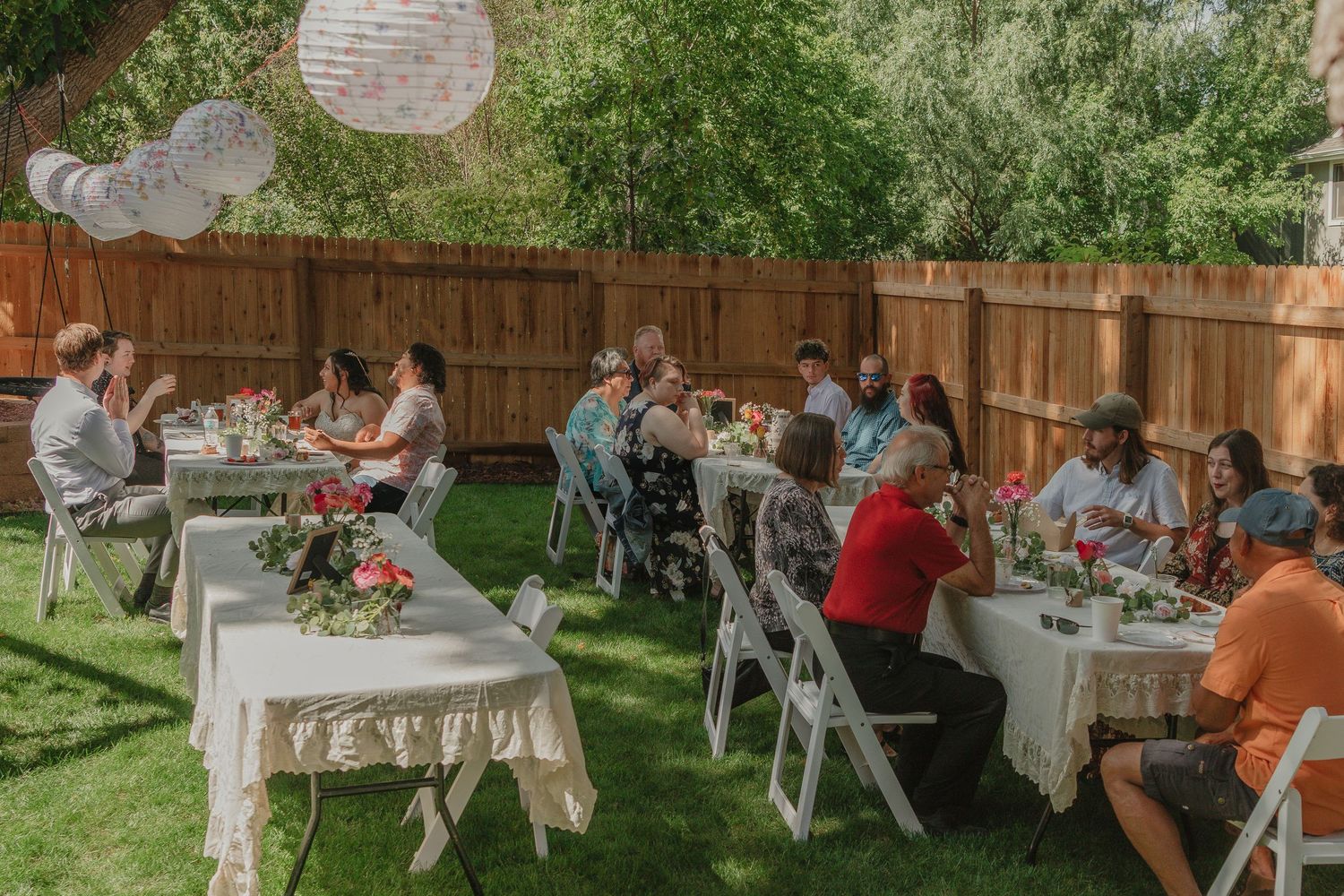 An outdoor garden party setup with white tables and chairs on a sunny lawn.