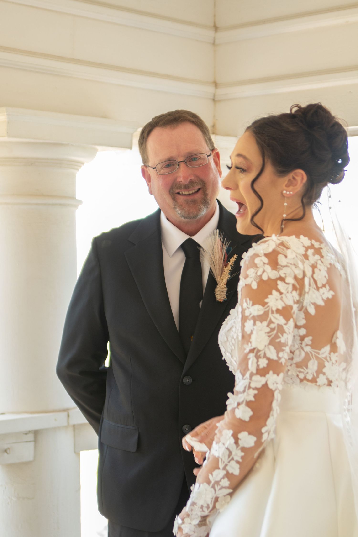 Emotional first look between people in formal attire in a bright white room.