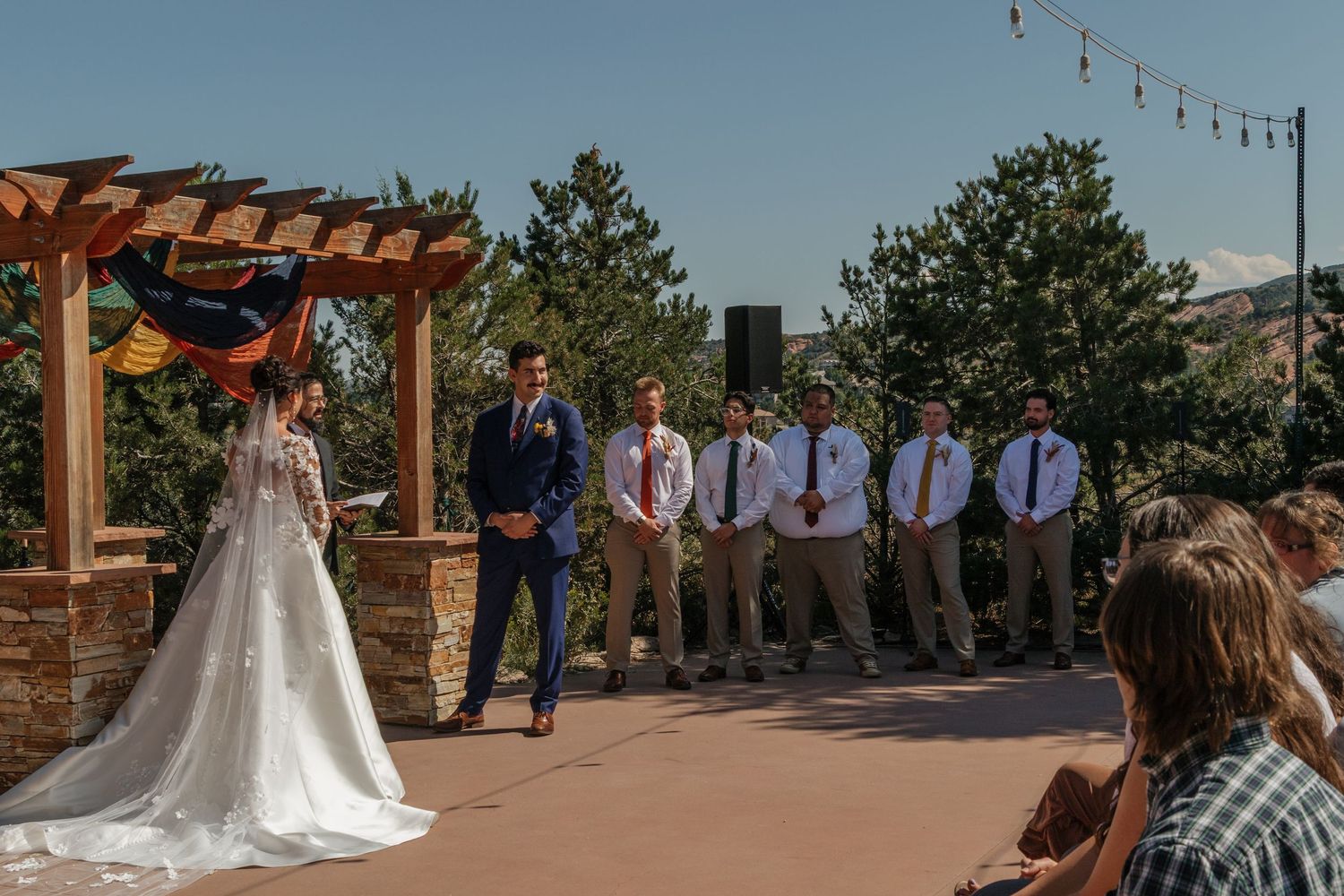 Outdoor wedding ceremony setup with wooden pergola against mountain backdrop.