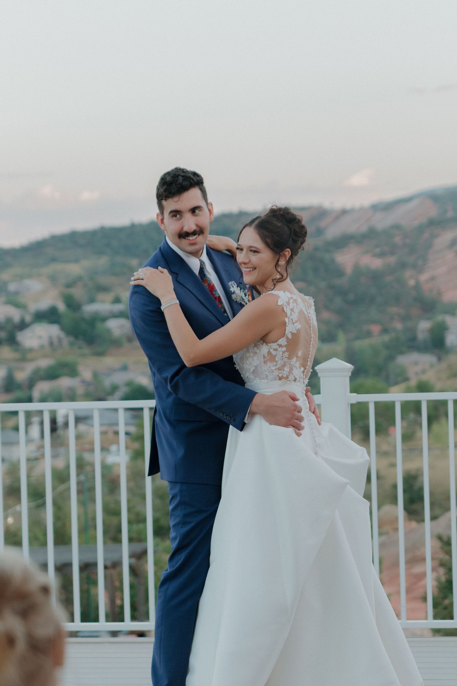 Romantic moment captured on outdoor balcony with mountain landscape in background.