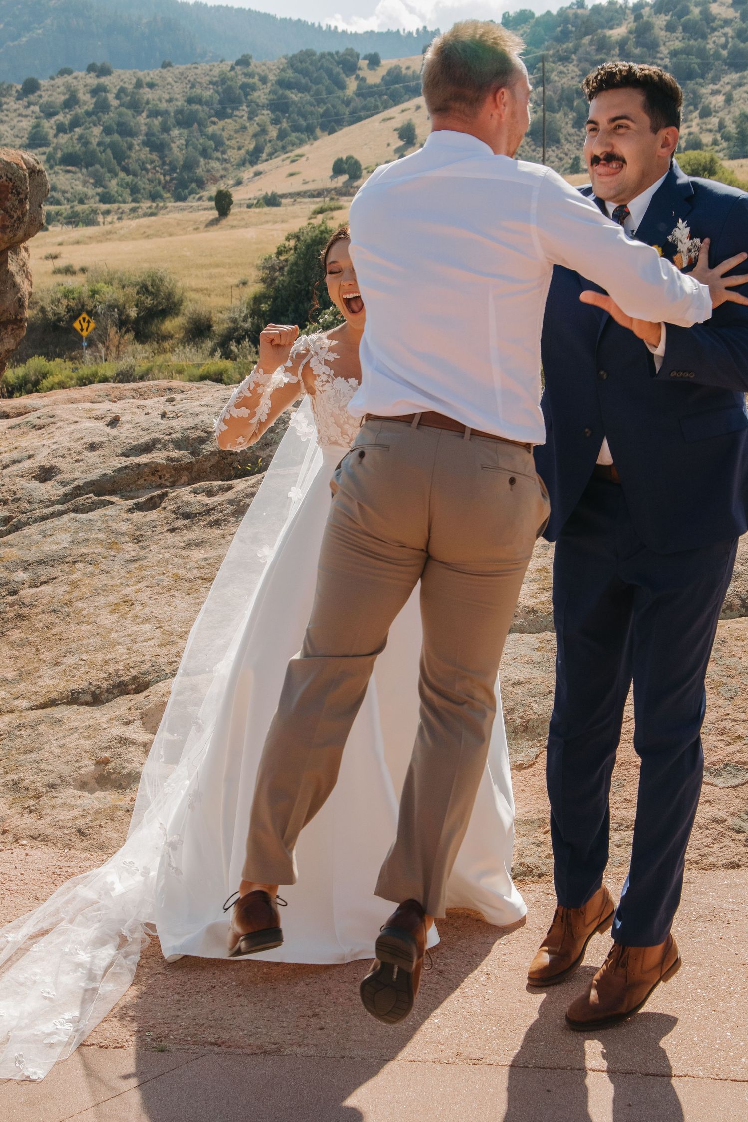 Wedding party poses on rocky mountain overlook with scenic desert views.