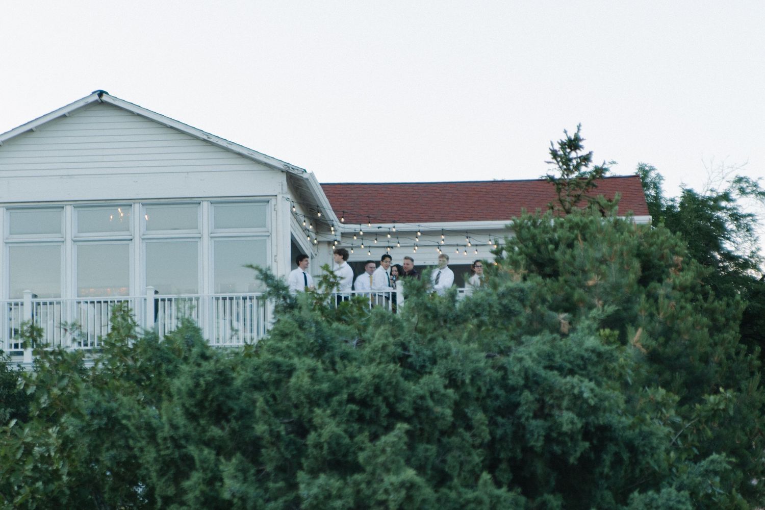 Exterior view of white residential buildings with green trees against clear sky.