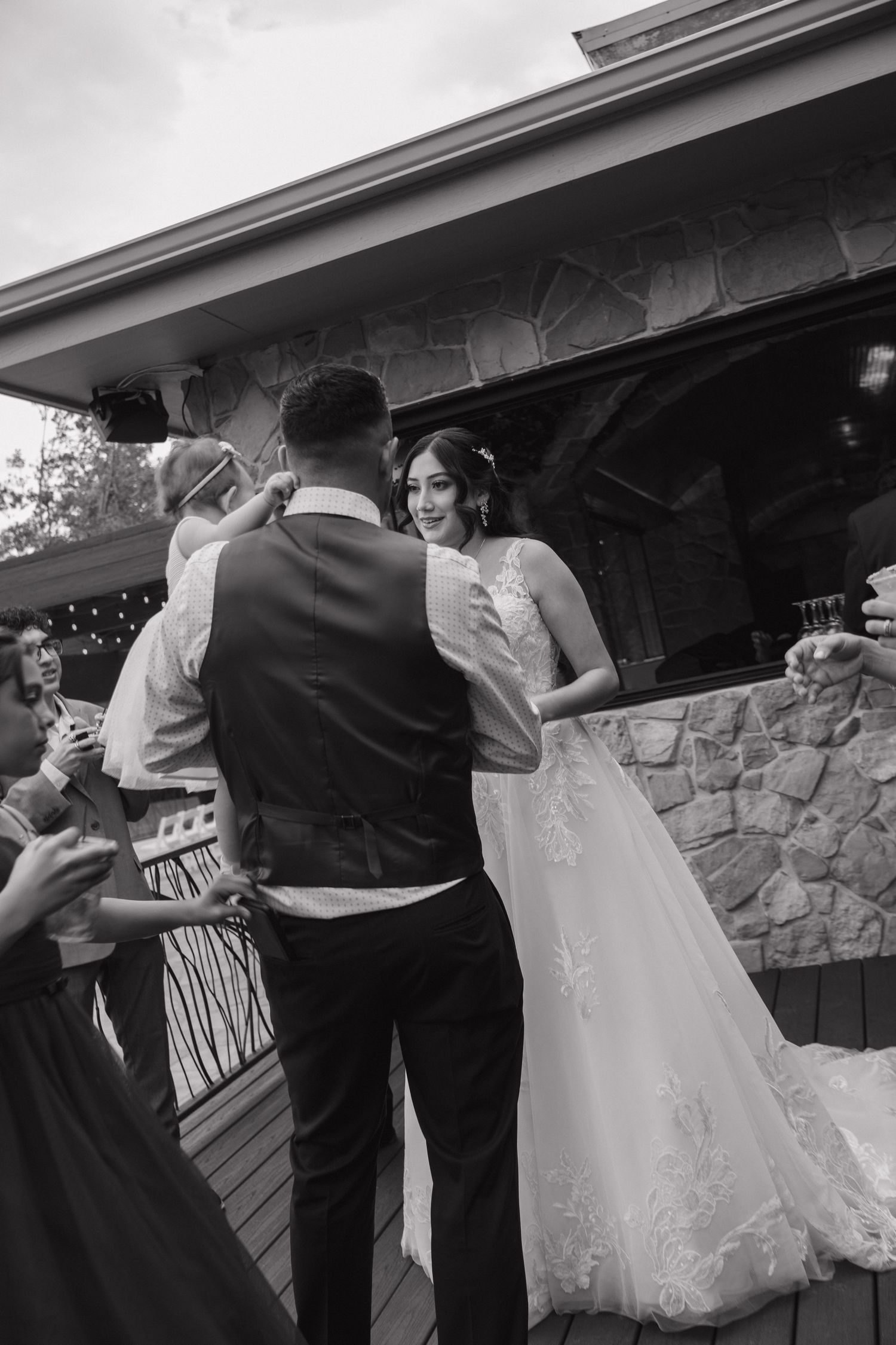 Bride and groom share a romantic moment on an outdoor patio during their wedding reception in black and white.