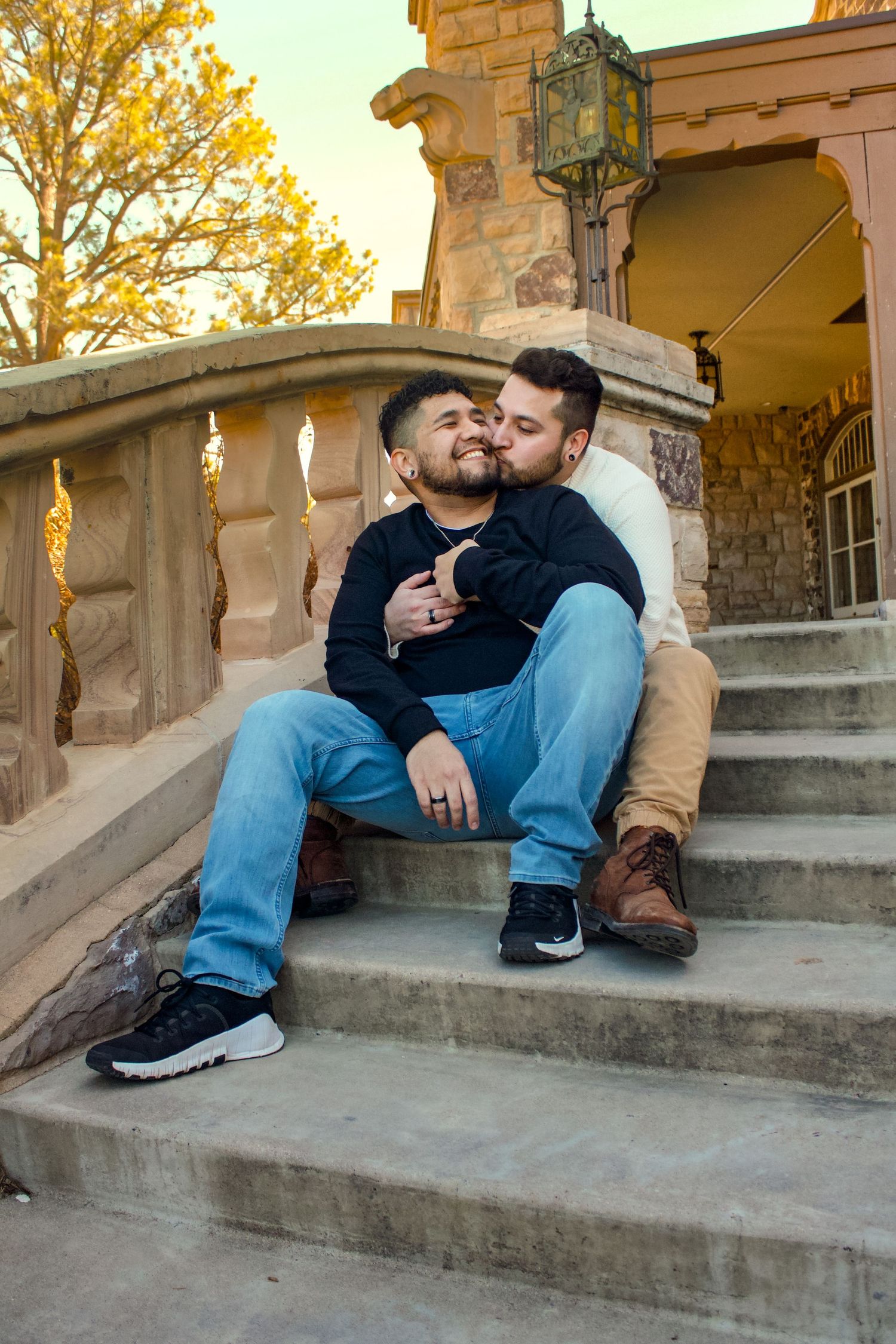 A couple sharing an intimate moment while sitting on stone steps during sunset.