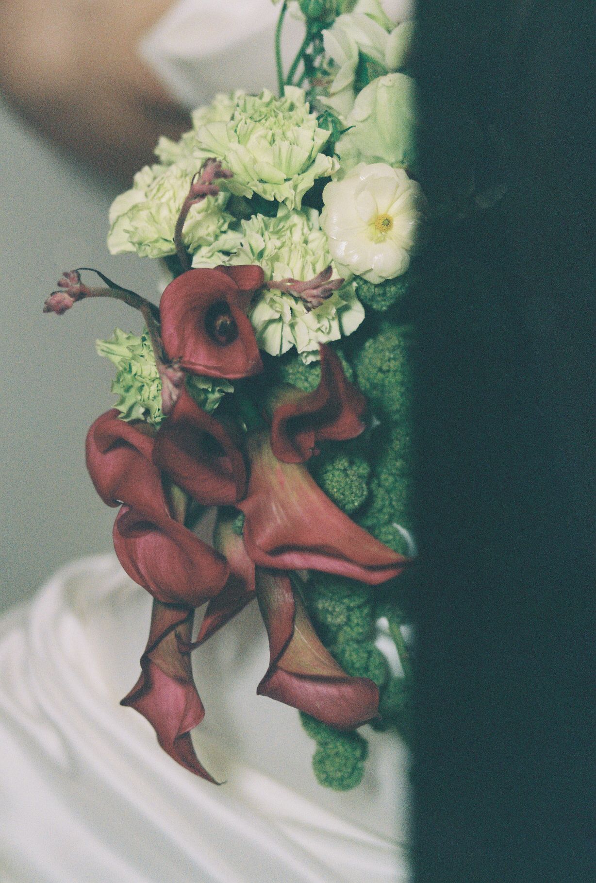 A creative floral arrangement featuring white blooms and dramatic red ribbon details.