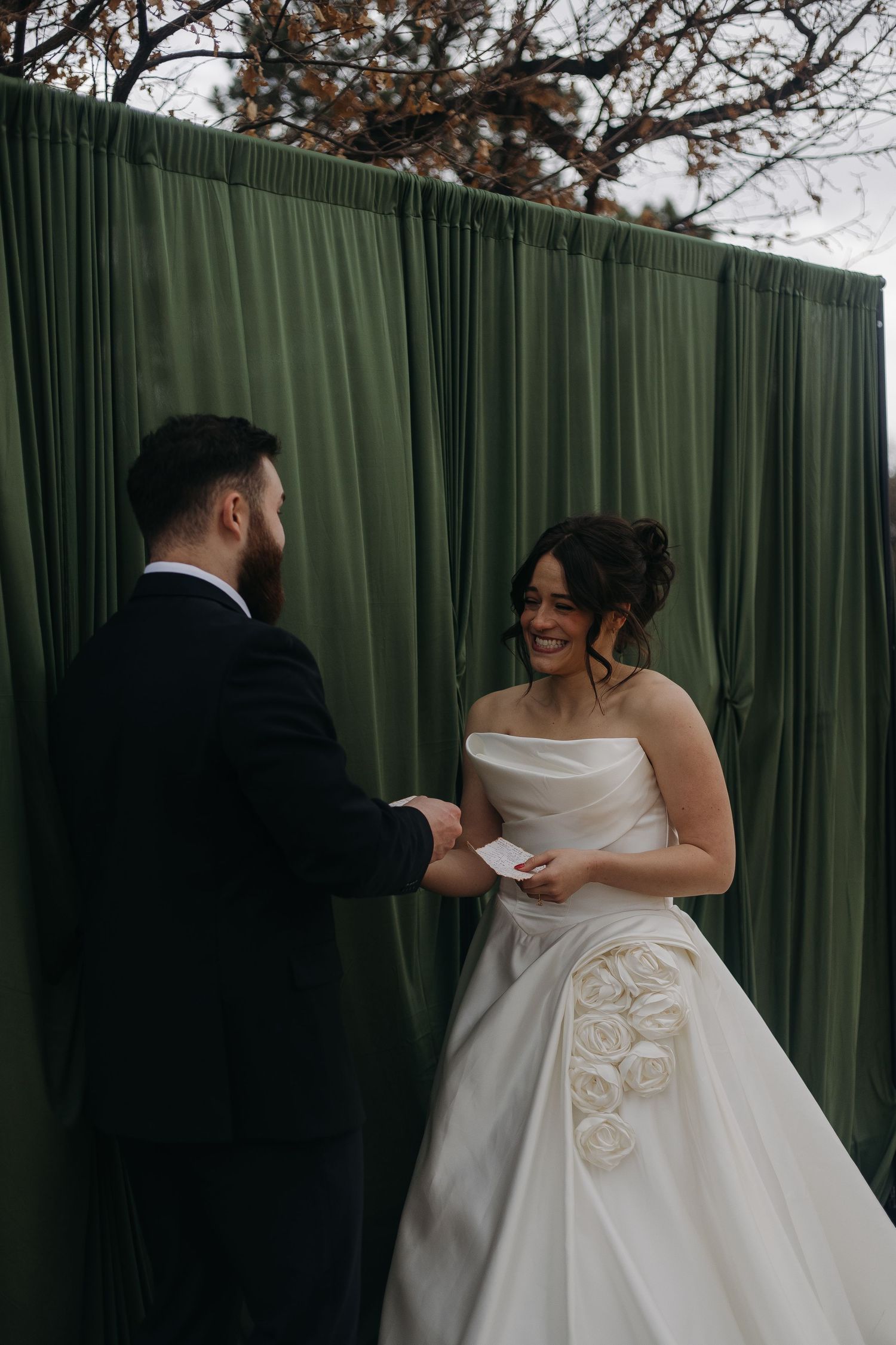 Couple sharing a private moment while exchanging vows in front of a green curtain backdrop.