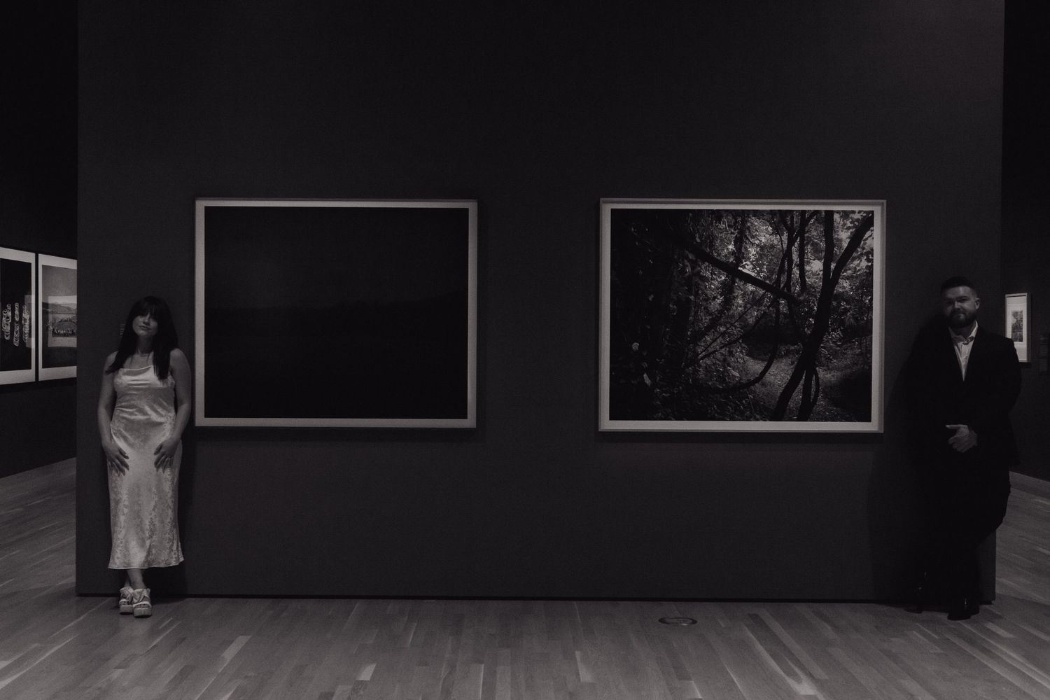 Art gallery wall displaying black and white photographs in a minimalist exhibition space.