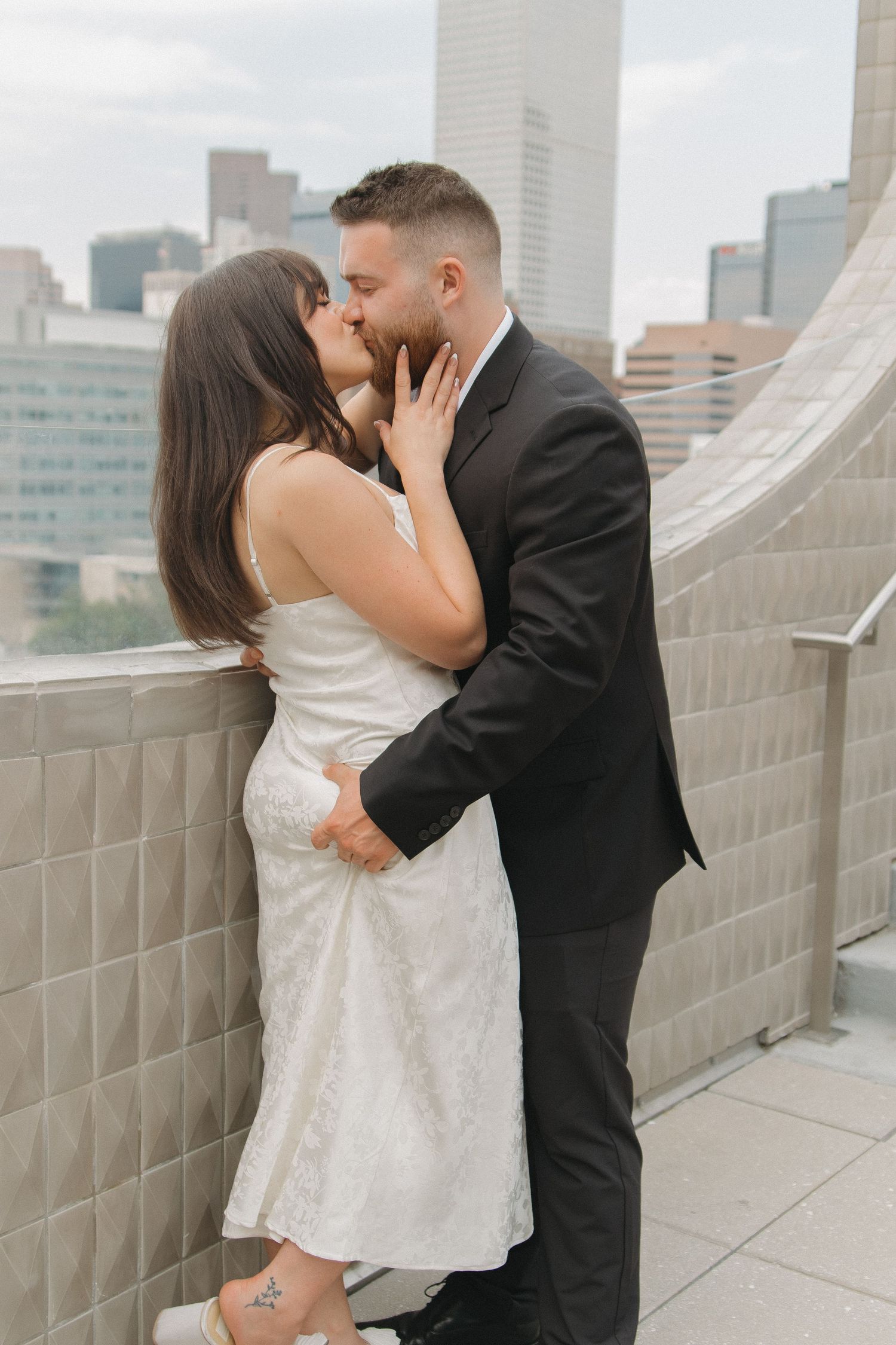 A romantic moment shared on a rooftop with modern city buildings in the background.