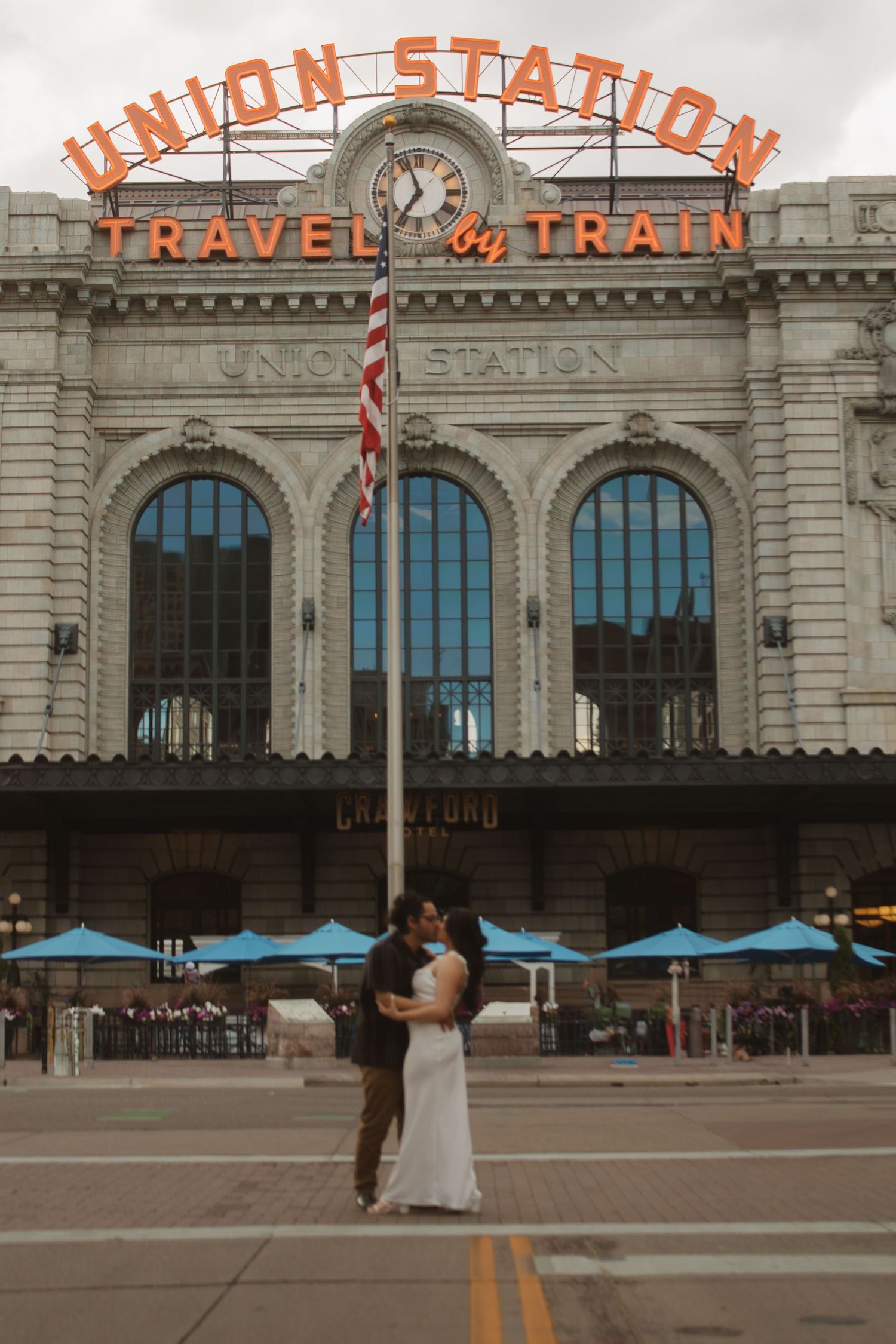 A couple sharing an intimate moment in front of the historic Union Station facade with its iconic neon signage.