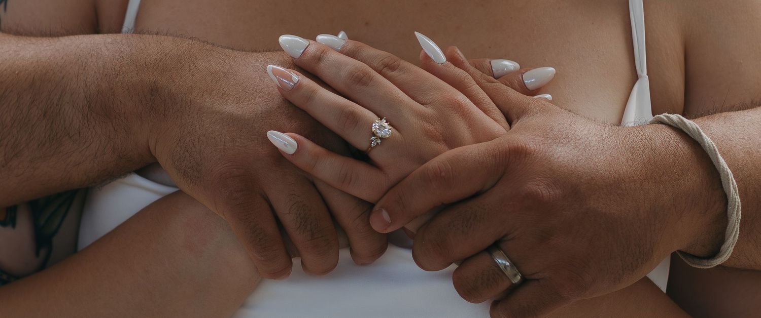 Close-up of hands wearing rings showing a tender moment between partners.