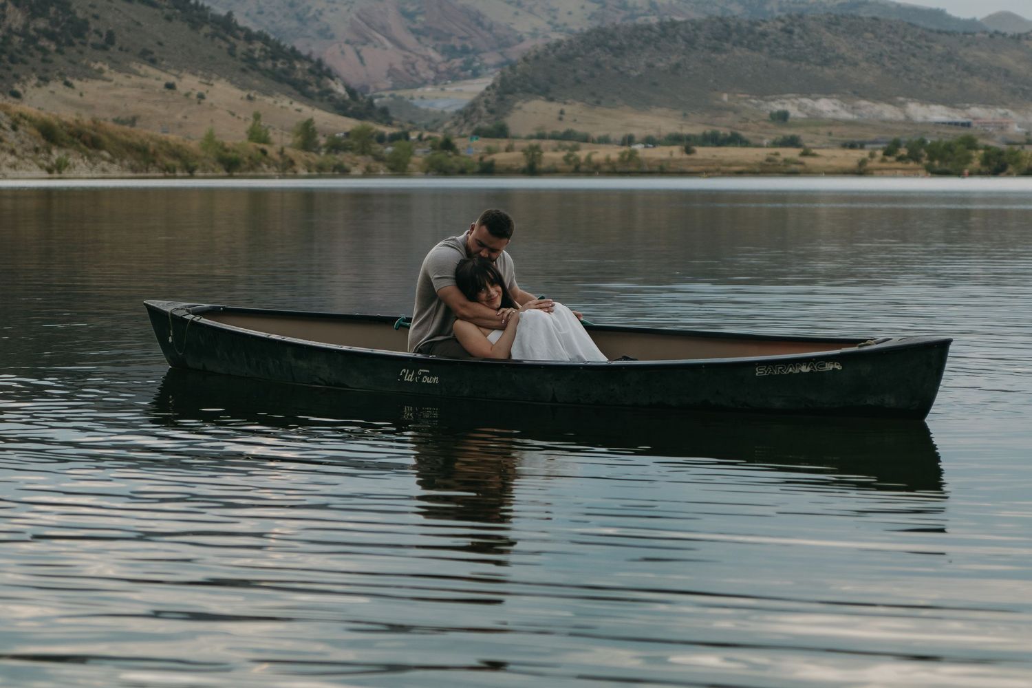 A romantic boat ride across calm waters with mountains and hills in the background.