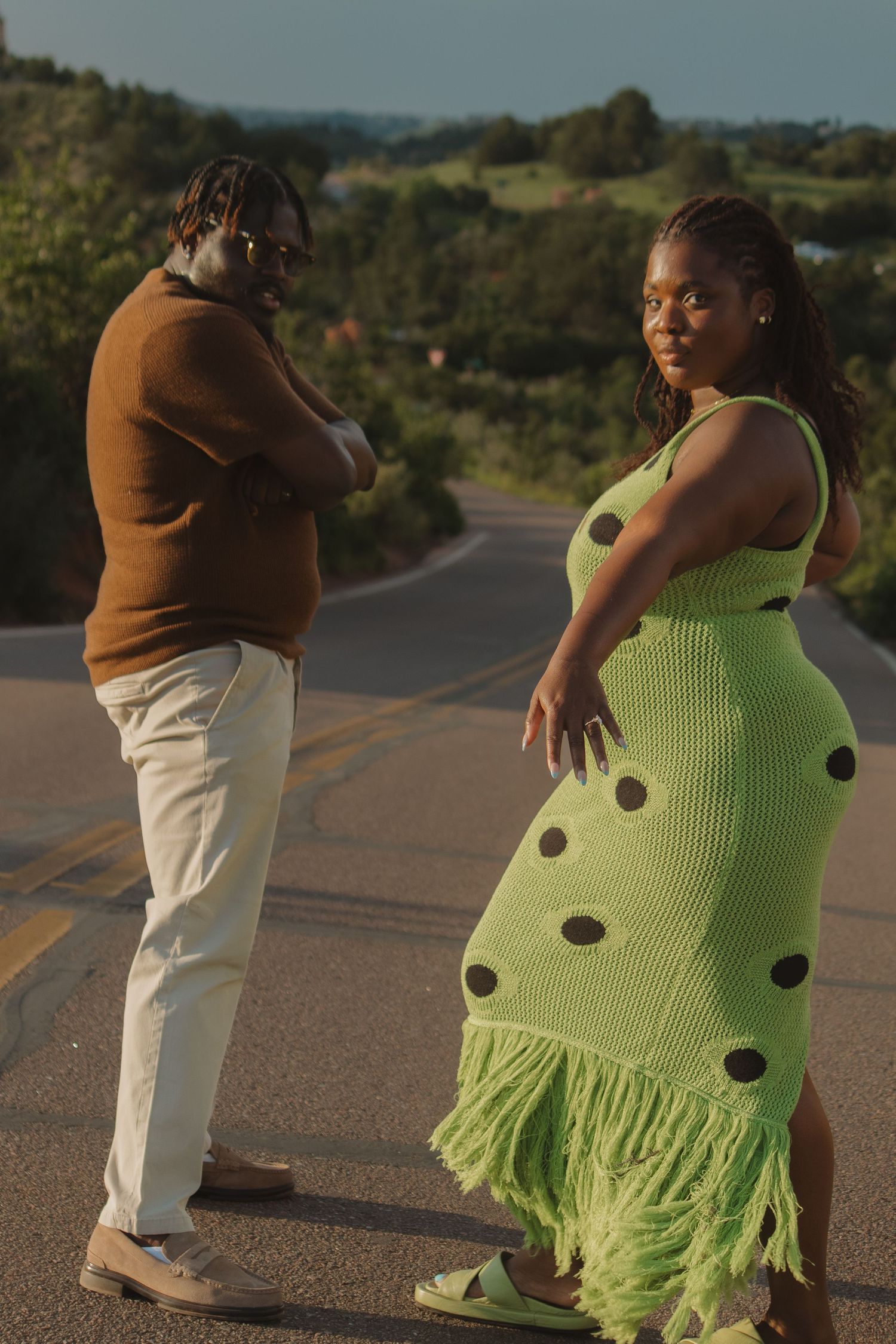 A couple walks together on a paved path, silhouetted against the setting sun.