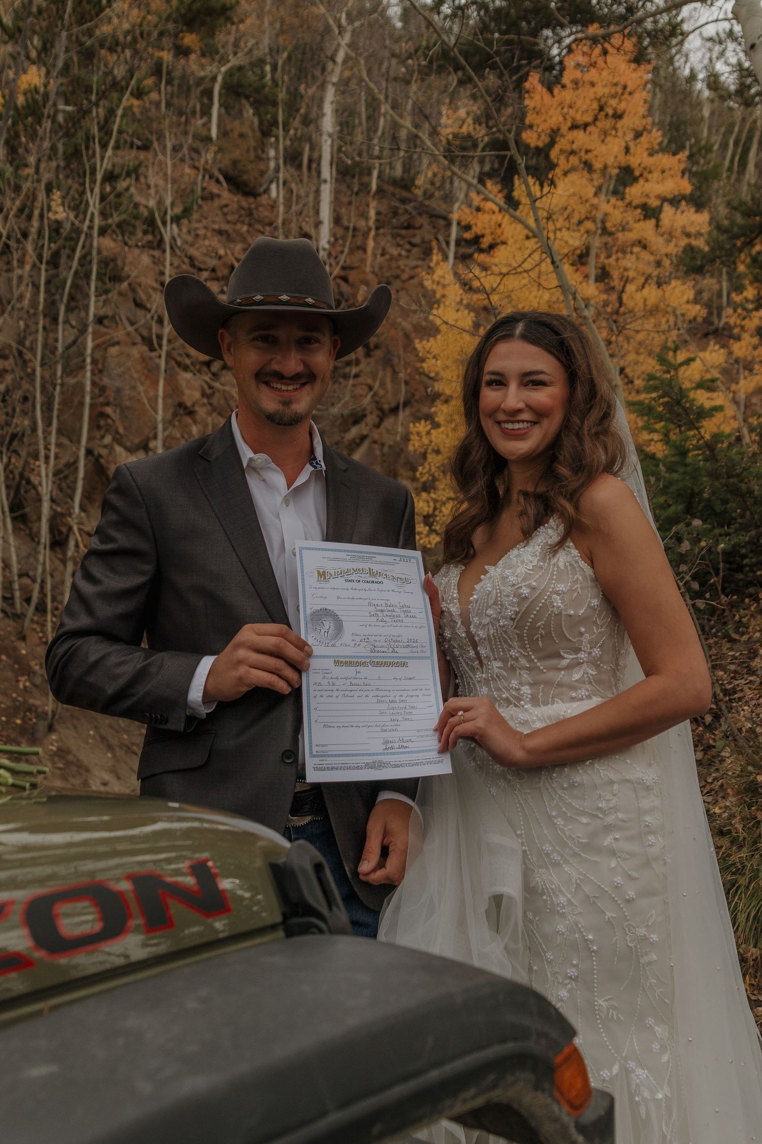 A couple shows off their marriage license in a series of candid moments with autumn foliage in the background.