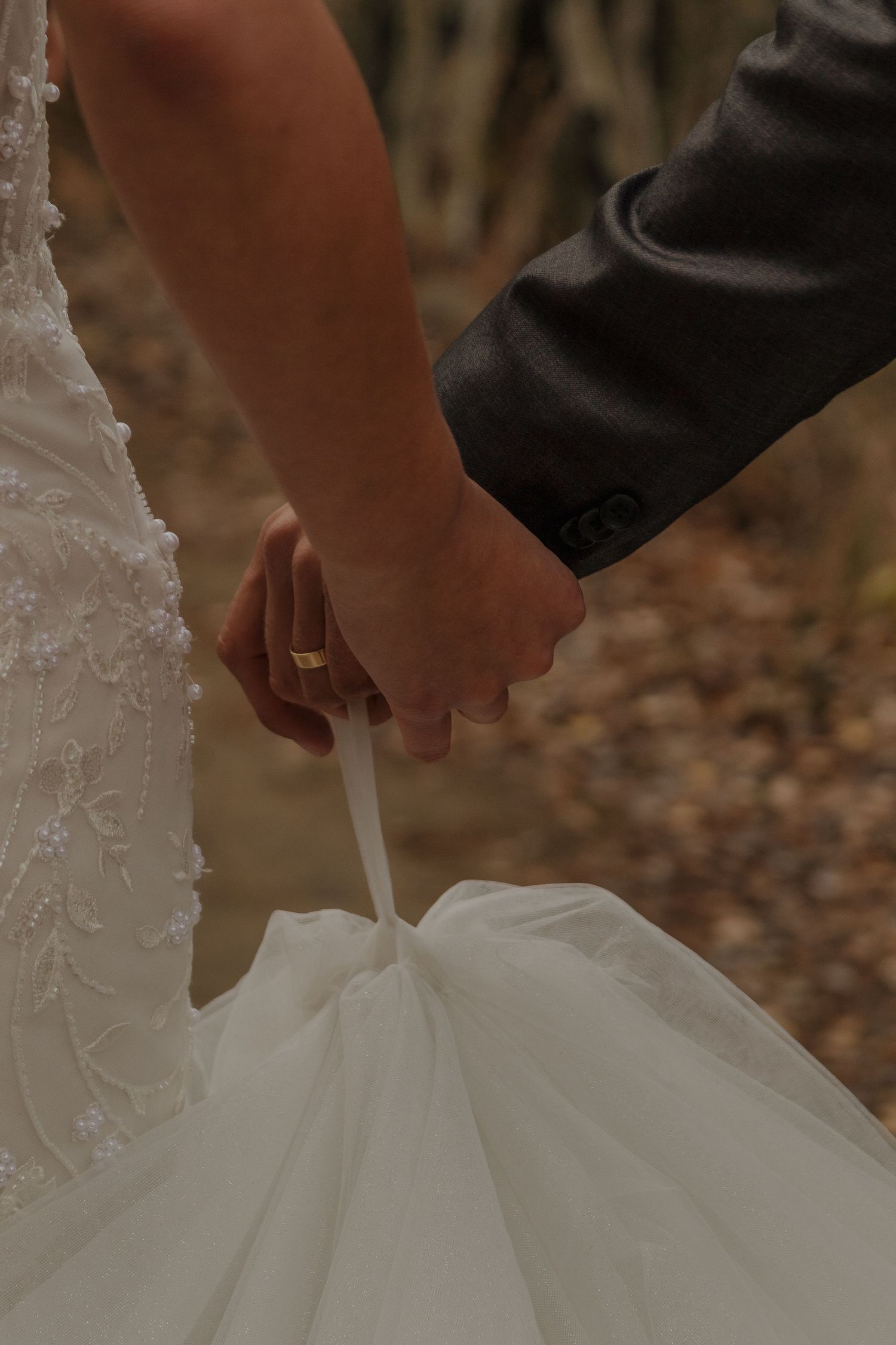 Close-up detail of a white lace wedding dress being adjusted.
