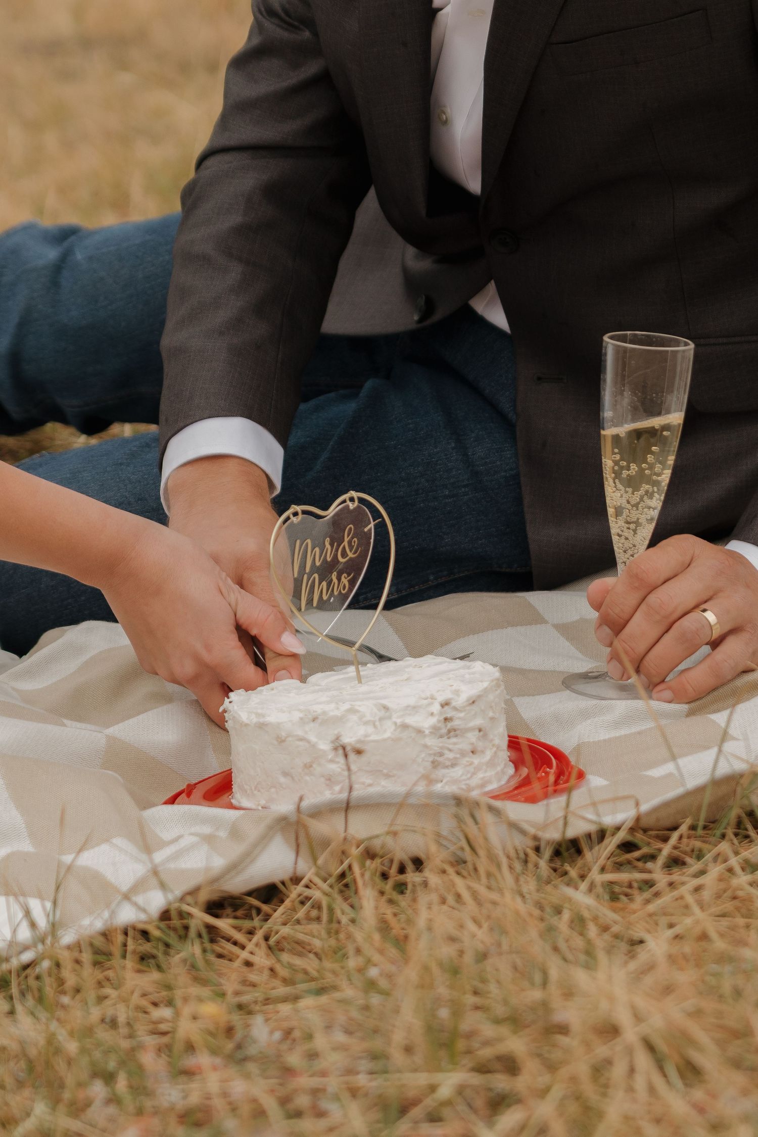 Wedding reception details with champagne glasses and place settings on grass.