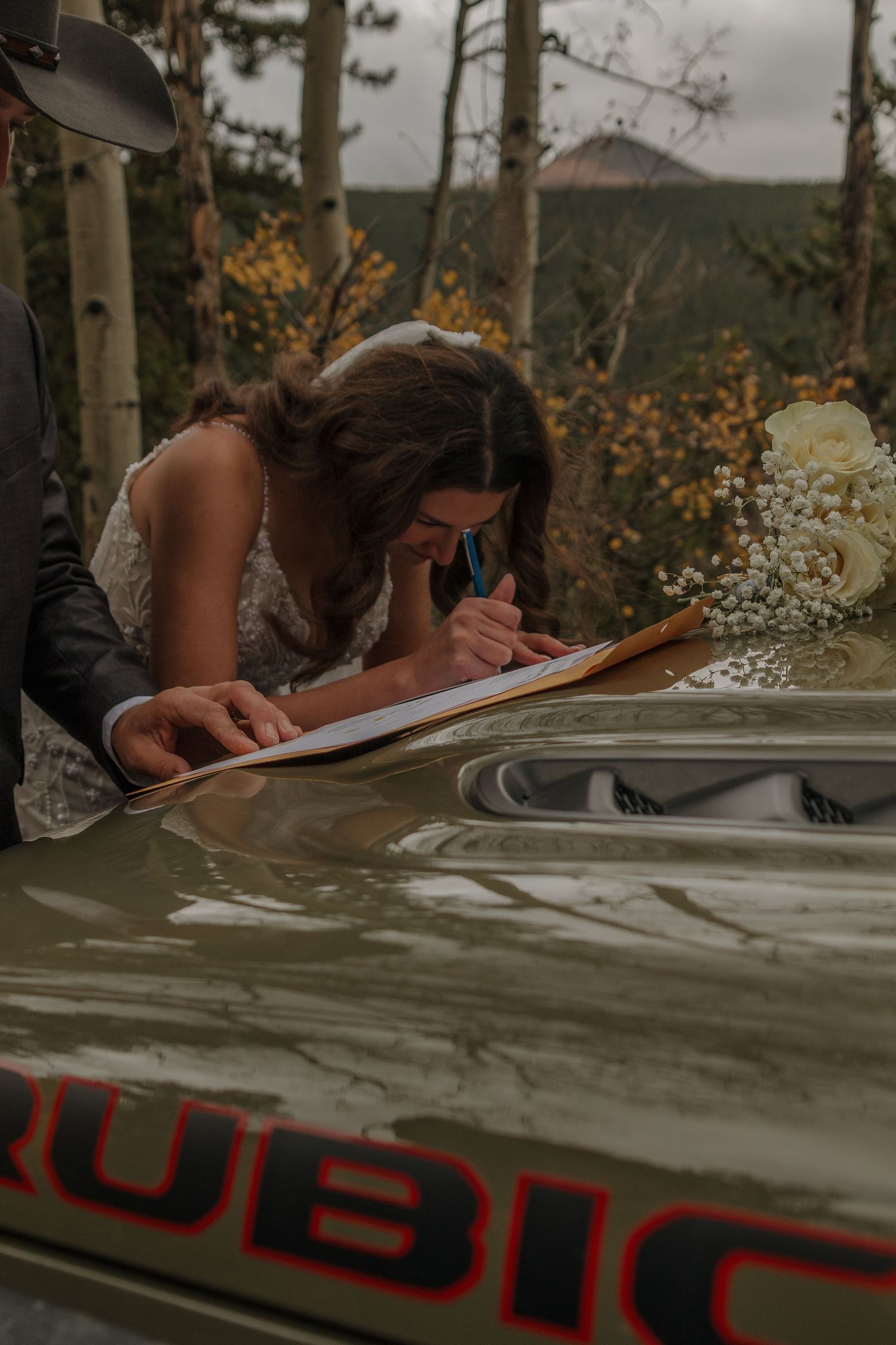 Close-up shot of signing a document on the hood of a vehicle in an outdoor setting.