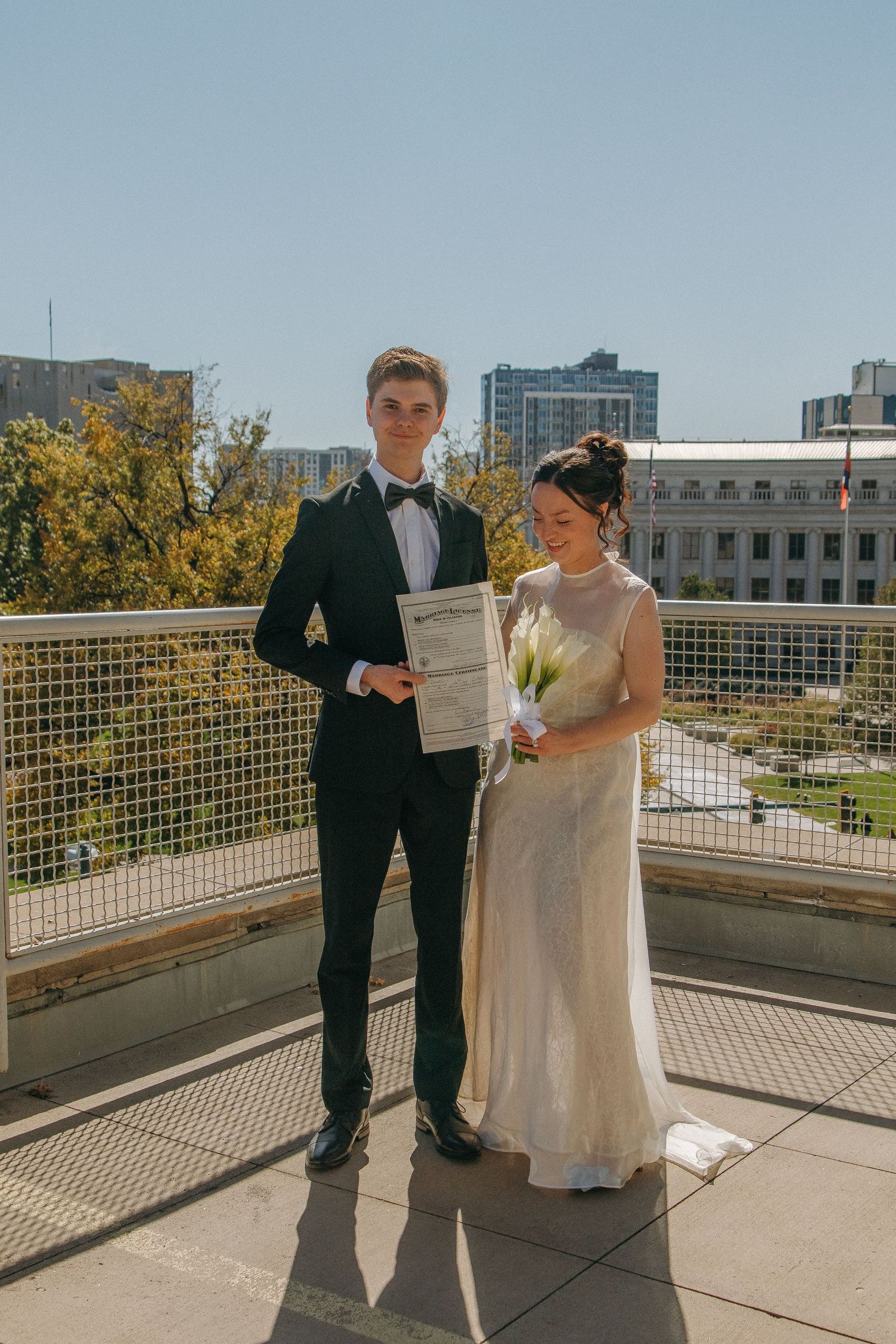 A wedding ceremony in progress on an outdoor terrace with yellow autumn trees visible in the distance.