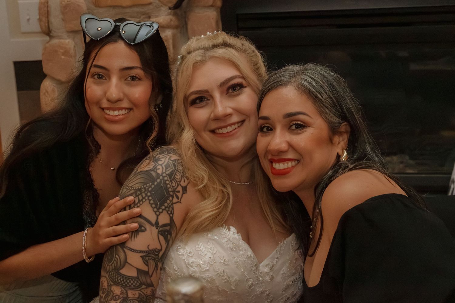 Group celebration photo at wedding reception near stone fireplace.