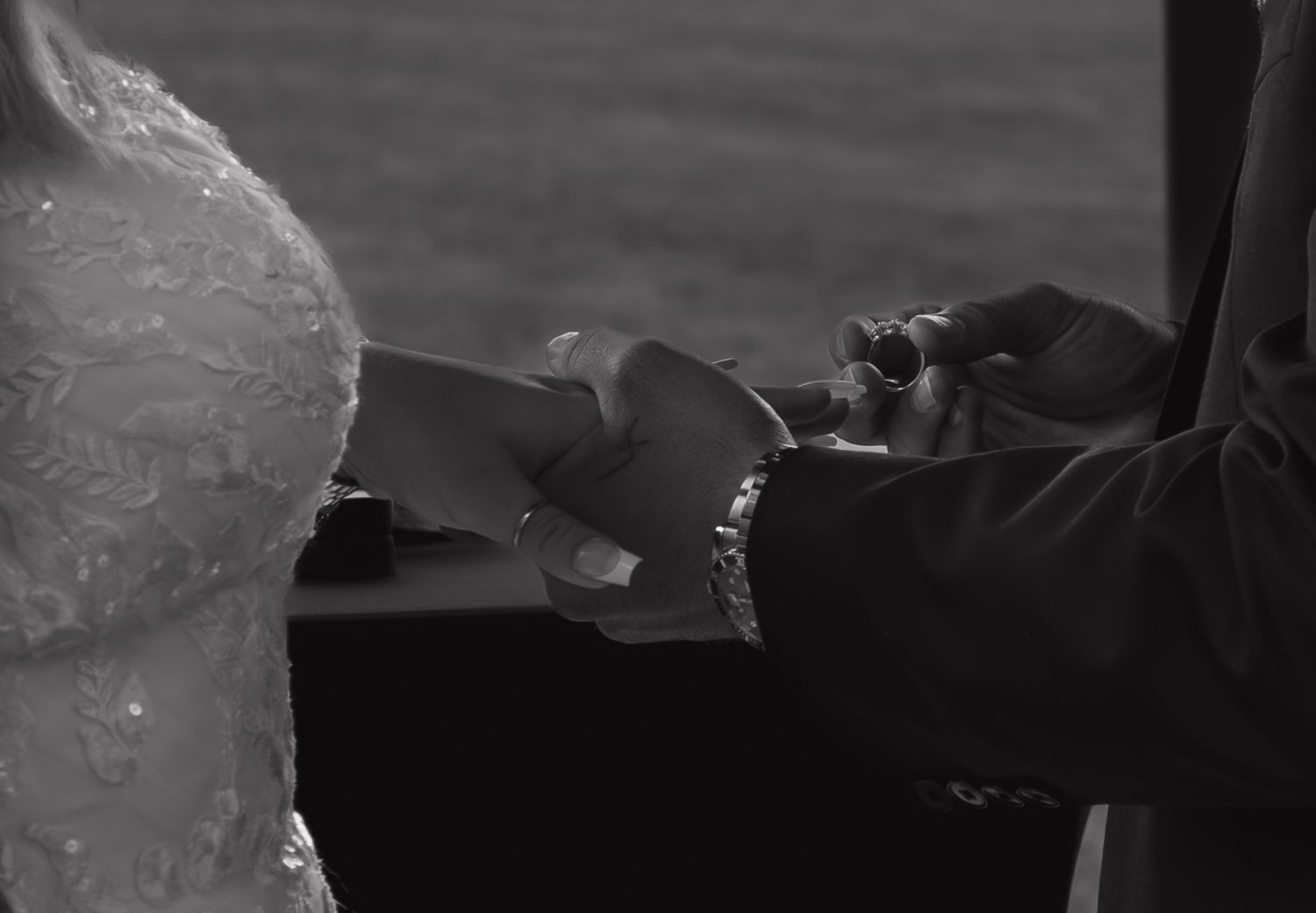 A dramatic black and white capture of wedding rings being exchanged during the ceremony.