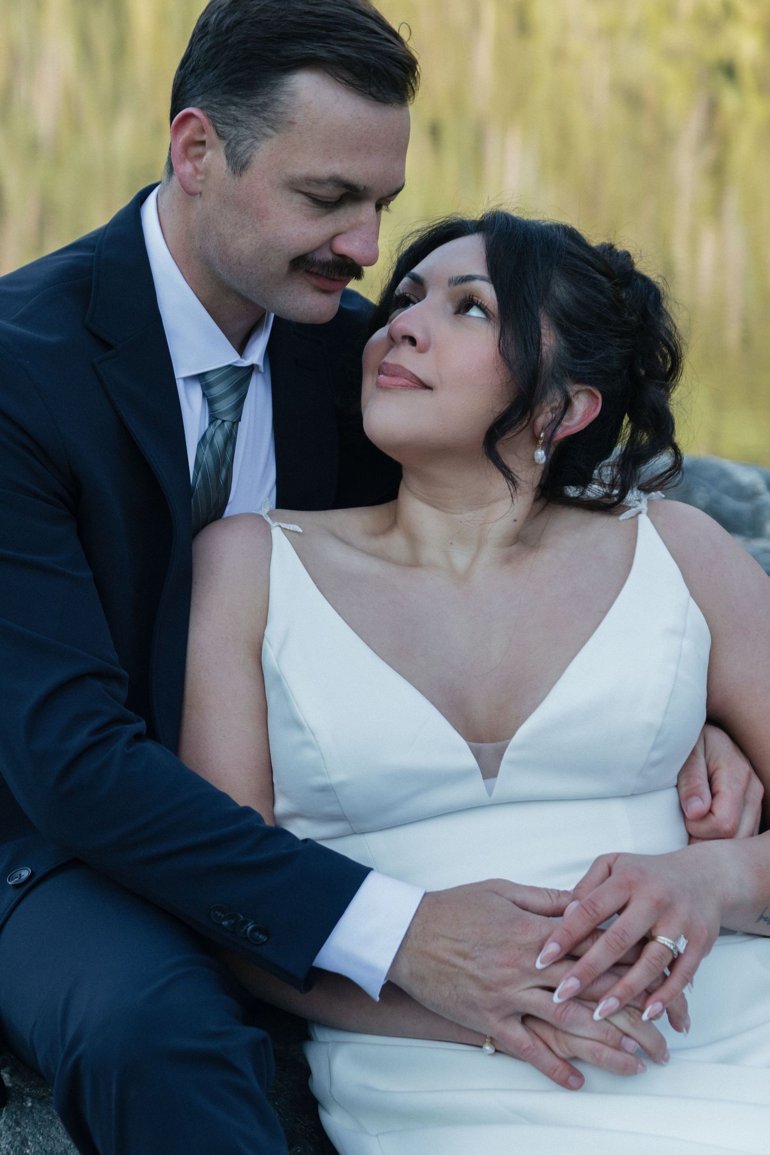 An intimate wedding portrait showing a tender moment against a golden mountain backdrop.