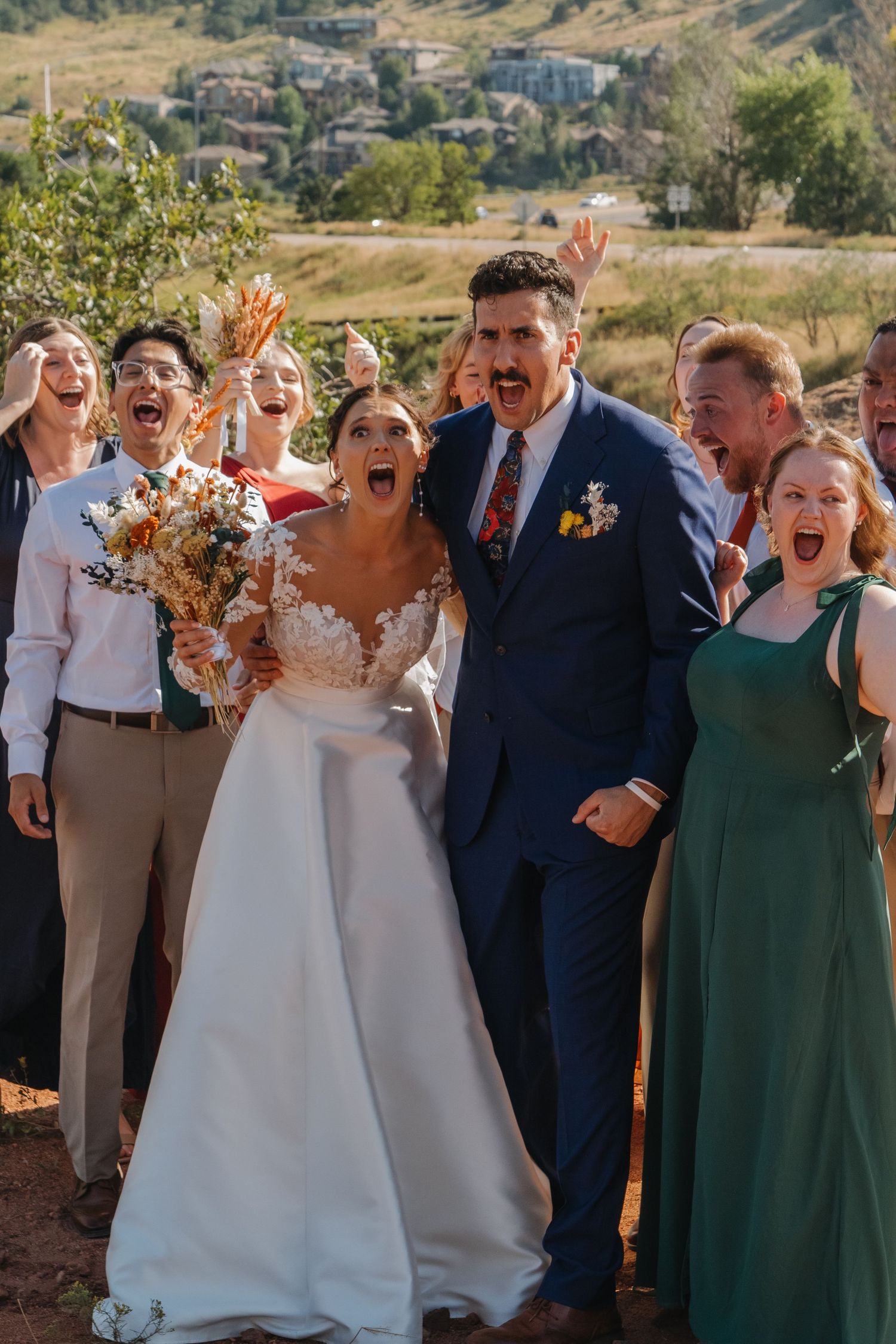 Energetic wedding group photo showing celebration and laughter in mountain setting.