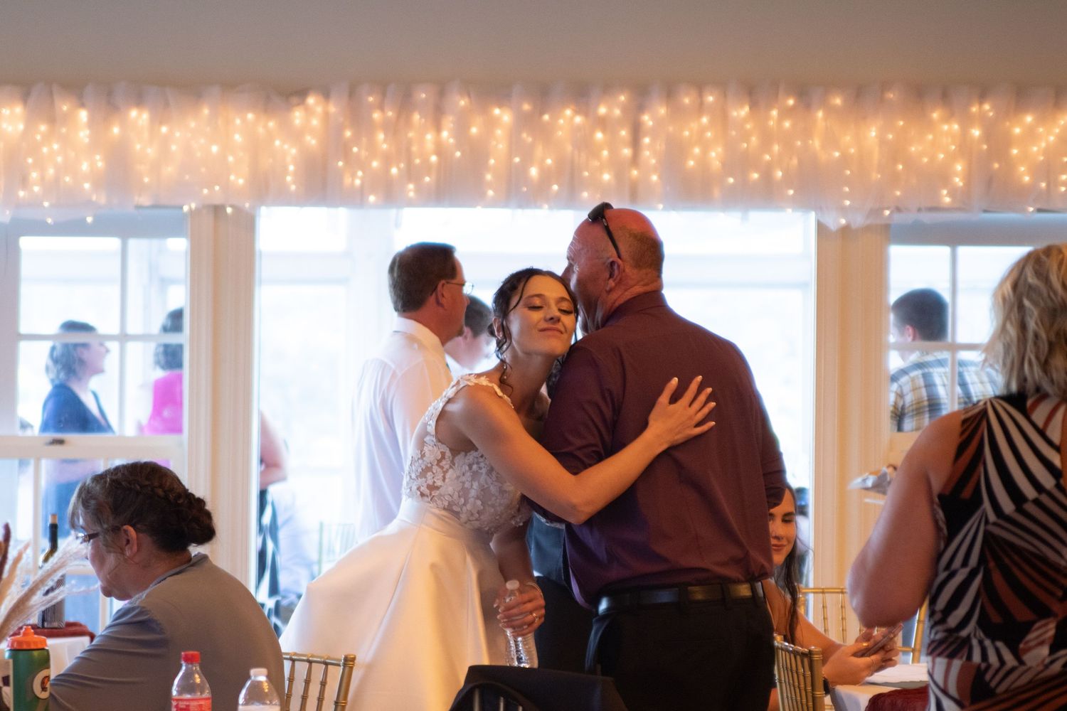 Reception hall glows with string lights as guests dance and celebrate.